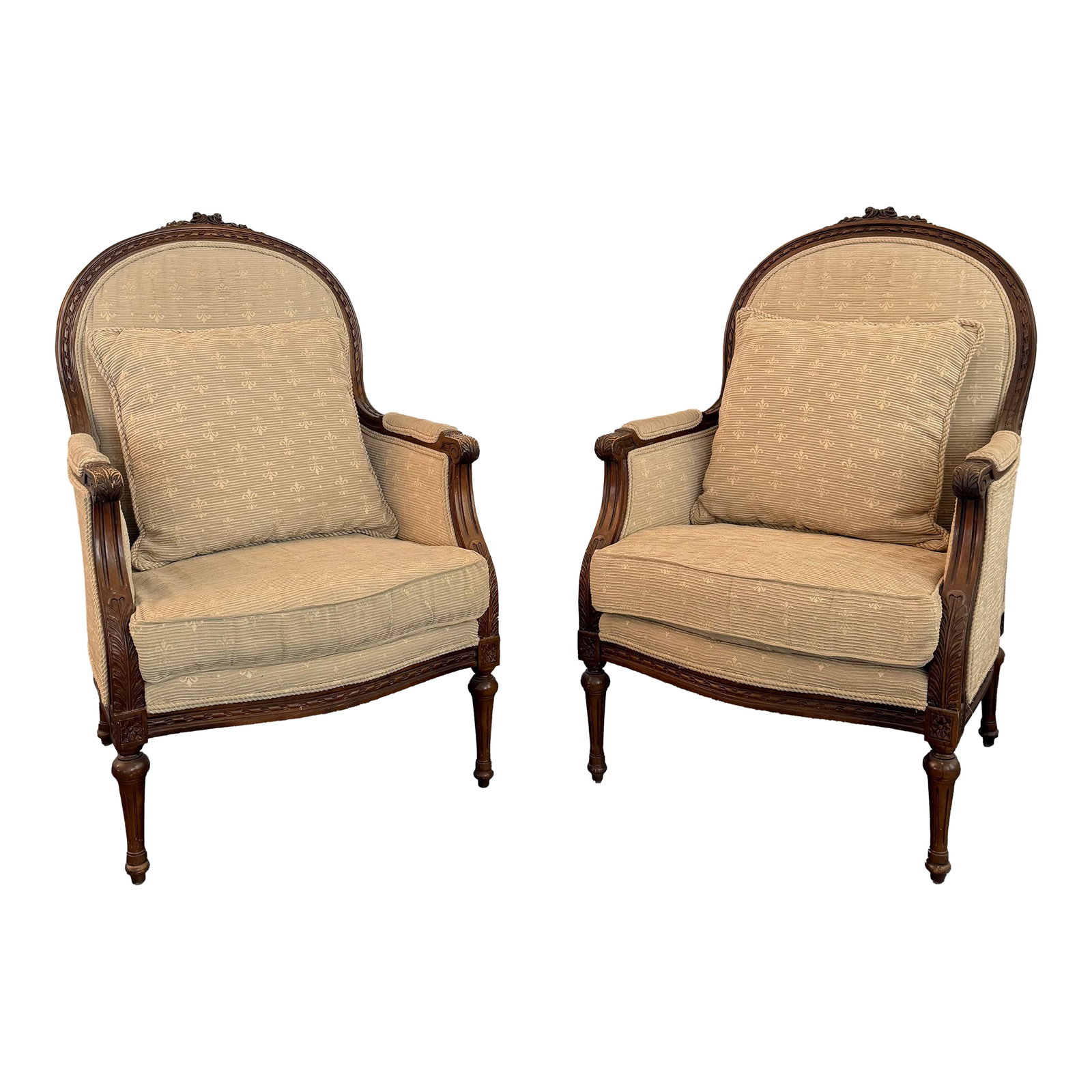 Pair of Mid-Century Louis XVI Style Carved Walnut Bergère Armchairs: This is a pair of walnut Louis XVI-style bergère armchairs produced circa the 1950s. The chairs combine classical European refinement with a timeless, sophisticated silhouette. Crafted with beaut
