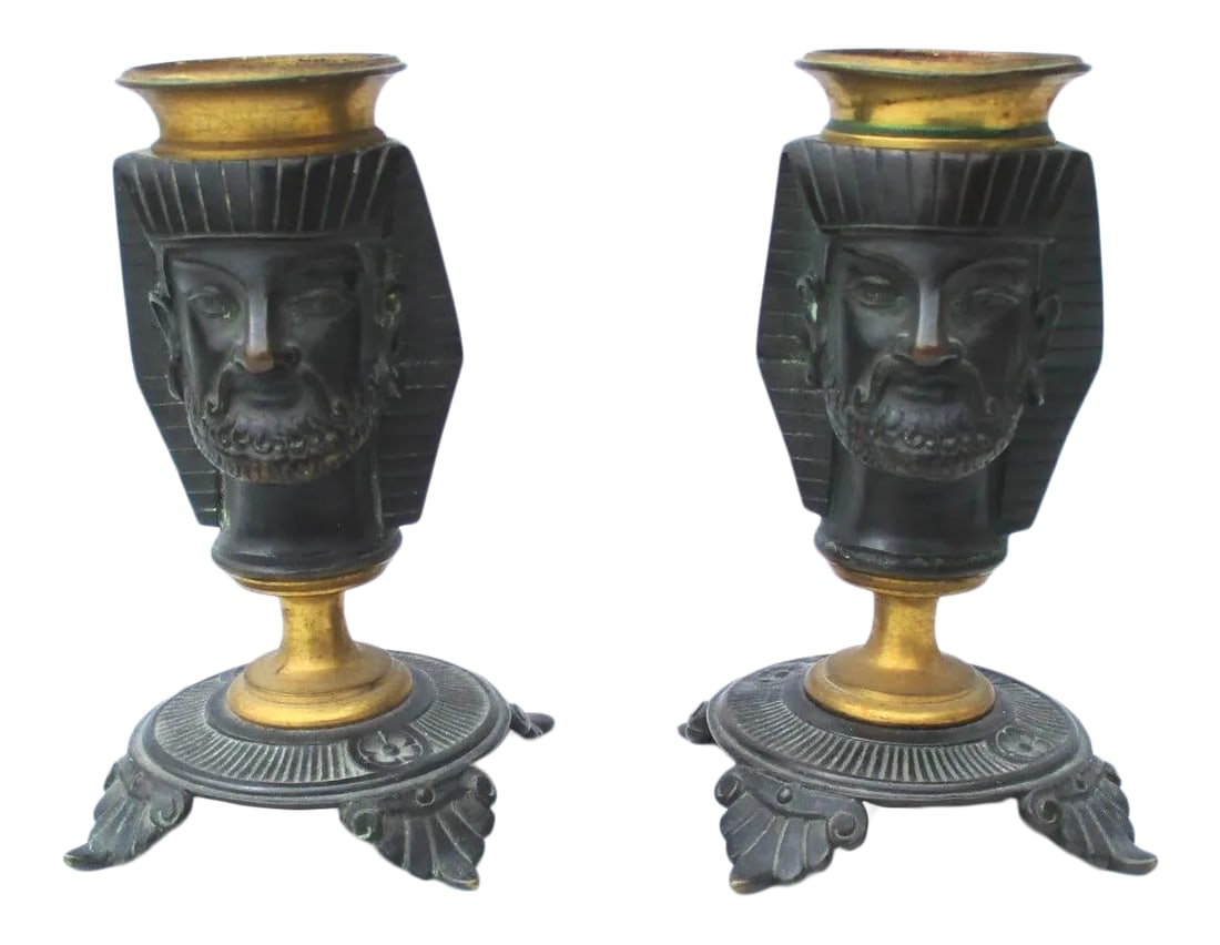 Egyptian Revival Bronze Candlesticks - a Pair: Pair of bronze Egyptian Pharaoh heads on elaborate Greek-style footed bases. Dark bronze patina with gilt candle holder and stem bases. Unmarked bronzes. Size 4.25" tall, base is 2.25" by 2.25"