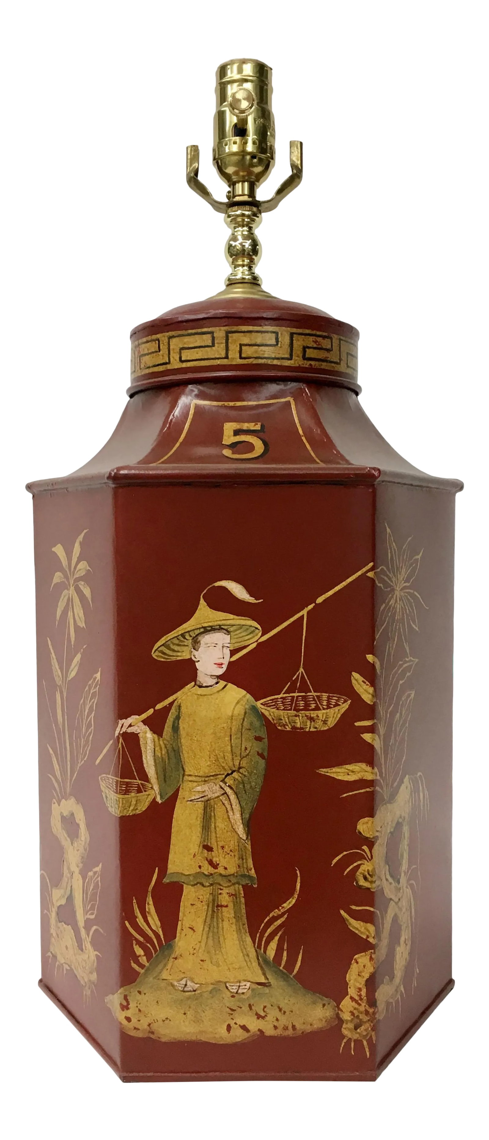 1970s Red Chinoiserie Tea Caddy Lamp: Hexagonal tole tea caddy lamp handpainted in gold with a Chinoiserie style featuring flowers and a Chinese figure balancing two baskets on their shoulder. This lamp is inspired by the English style te
