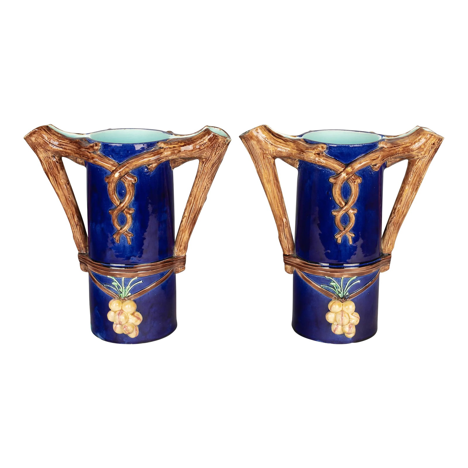 1920s French Majolica Pitchers or Vases - a Pair: A pair of French Majolica vases or pitchers, each with double tree branch form handles and spouts. Deep, rich cobalt blue glaze with aqua interior and grape clusters. Minor glaze loss. Condition: