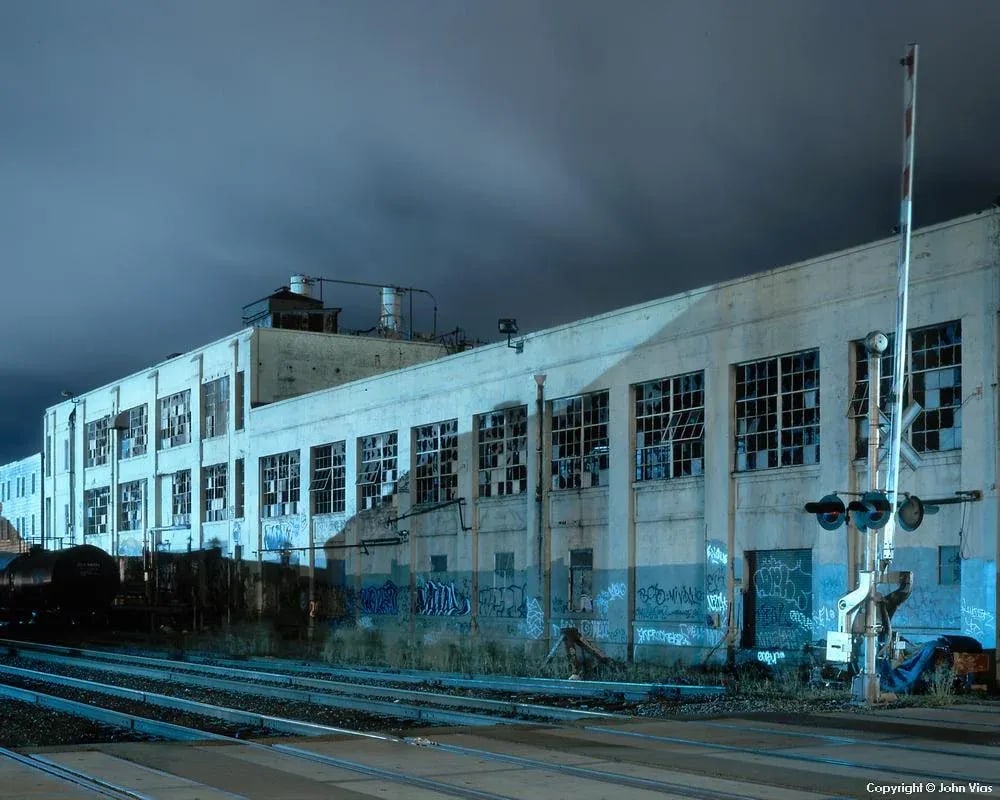 Contemporary Night Photograph "Warehouse" by John Vias: Note from the artist, John Vias: "This building's apparent stability is belied by its broken windows." This 8" x 10" archival color photograph is presented in a 20" x 16" archival white mat. Condition