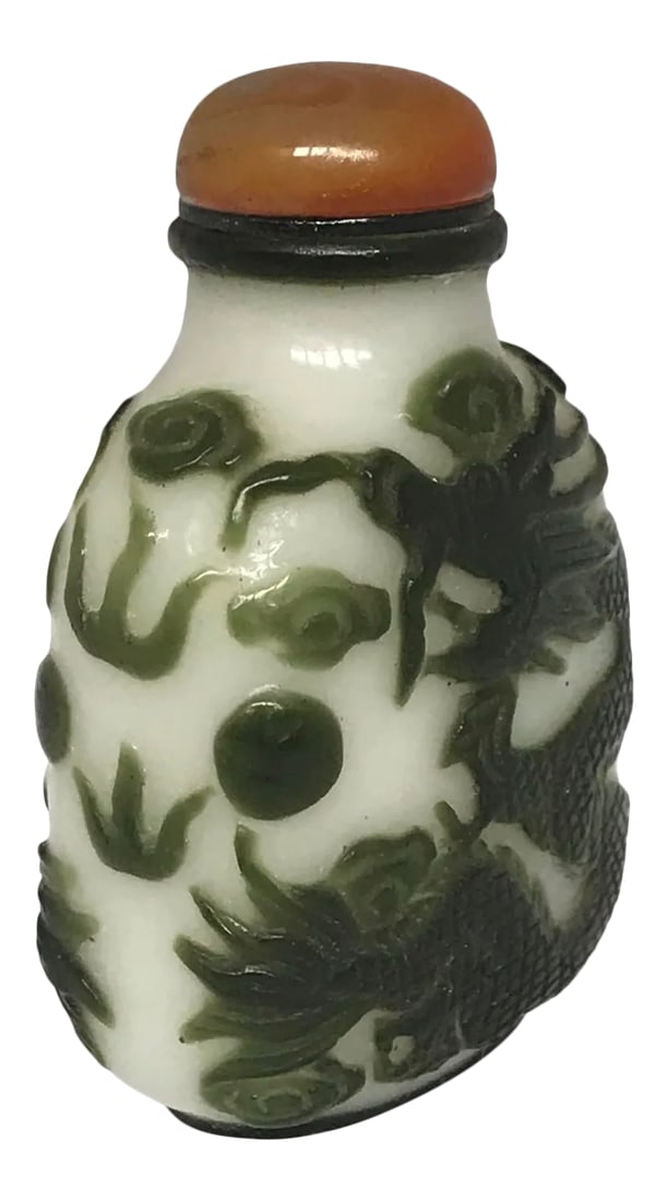 Antique Beijing Glass Snuff Bottle With Green Overlay of Dragons: The bottle us a flattened oblong form with flat lip and recessed convex foot surrounded by an oval foot trim. A similar trim is ringed around the top. Two dragons chasing a precious pearl among cloud 