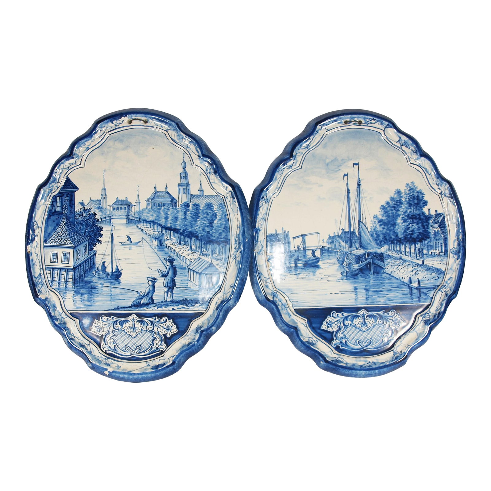 Two Antique Dutch Royal Makkum Delft Blue & White Plaques W/ Dutch Fishing Vessels: Two antique Dutch Royal Makkum Delft blue and white plaques. Image is of a fishing boat in the canal and two men fishing in the same canal. Plaques are shaped elliptical form with raised edge. On the