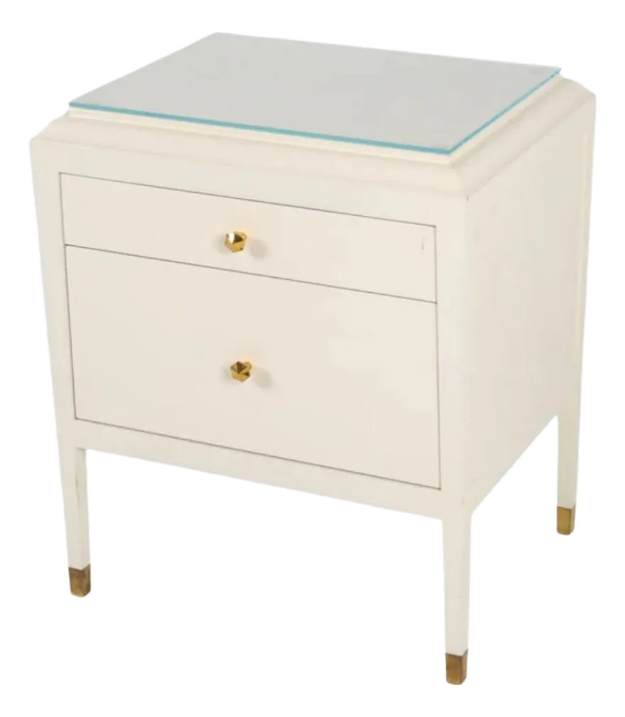 Contemporary White Lacquered Nightstand With Brass Fittings and Glass Top: A contemporary white lacquered nightstand with brass fittings. Stylish and functional, the table has two drawers, one slim and one deeper, and a glass top. The drawer pulls are faceted brass and the n