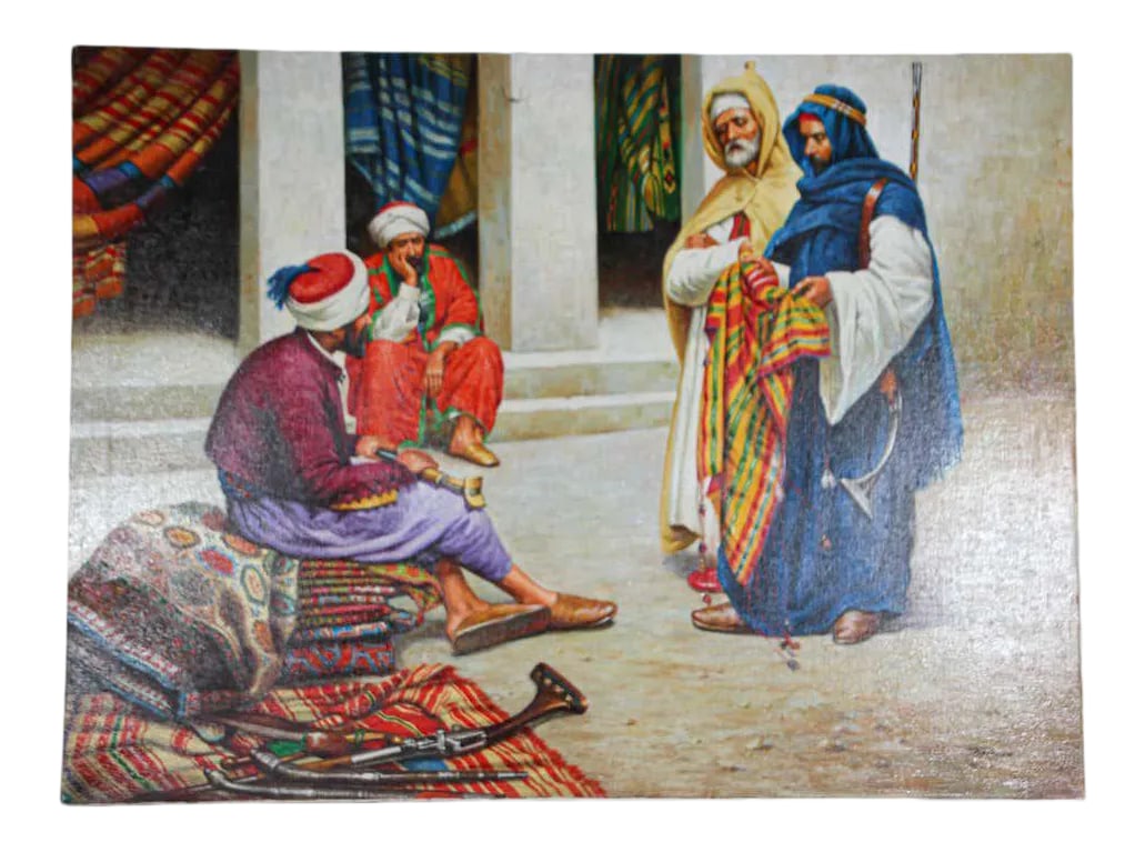 Moroccan Orientalist Oil Painting of a Rug Market: Moroccan orientalist oil on canvas painting of a 19th century Moroccan rug market scene with an sellers seating on a pile of carpet and two other men wearing traditional colorful robes standing and