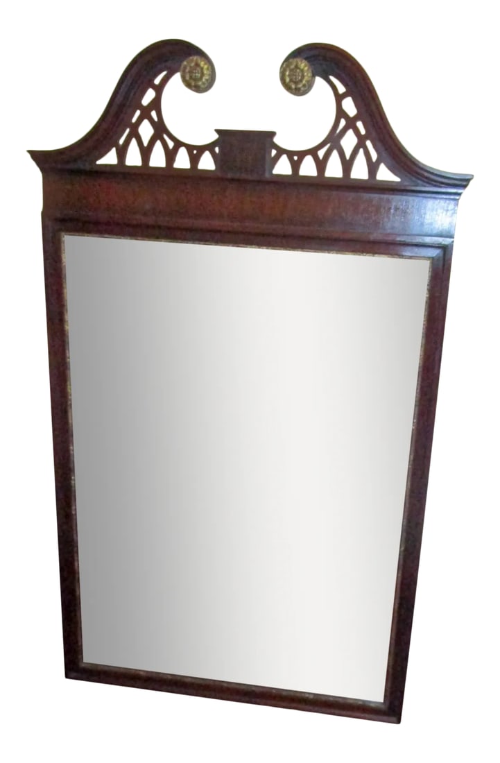American Mahogany Federal Style Broken Pediment Wall Hanging Mirror: Federal style wall mirror, circa 1920s. Made from mahogany and featuring a scrolled broken pediment, flanked by gold sunflower rosettes and cutwork. The inside of the frame has a thin carve gold