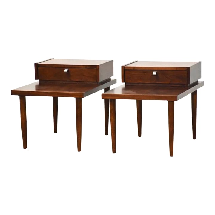 American of Martinsville End Tables - a Pair: A pair of mid century modern walnut two tiered end tables made by American of Martinsville. Professionally refinished. Lower tier height is 16". 20" wide. 28" deep. 21.25" tall. Condition:
