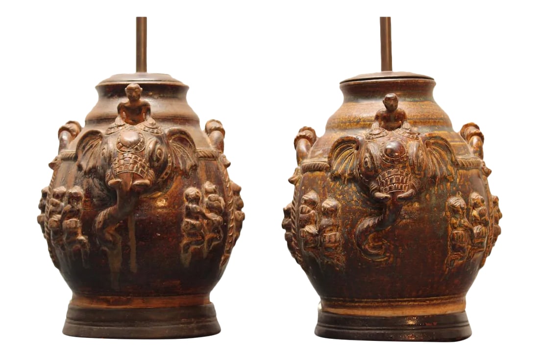 Pair of Vintage East Indian Ceramic Vessel Lamps With Elephant & Rider Motif - Mahogany Bases: A striking pair of vintage ceramic vessel lamps, likely of East Indian origin, featuring exquisitely detailed sculptural decoration and beautiful glazed finishes. Each lamp showcases a central human f