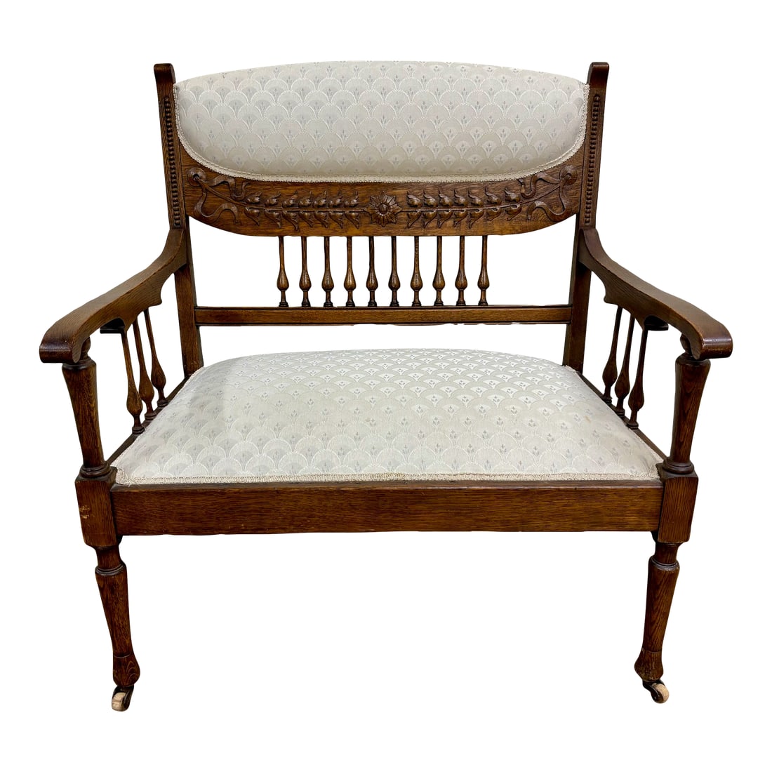 Antique Carved Spindle Back Carved Upholstered Settee: This is a stunning antique, believed to be Edwardian from the early 1900s, carved spindle back carved upholstered settee with white geometric upholstery and carved floral and ribbon back. Rolls on