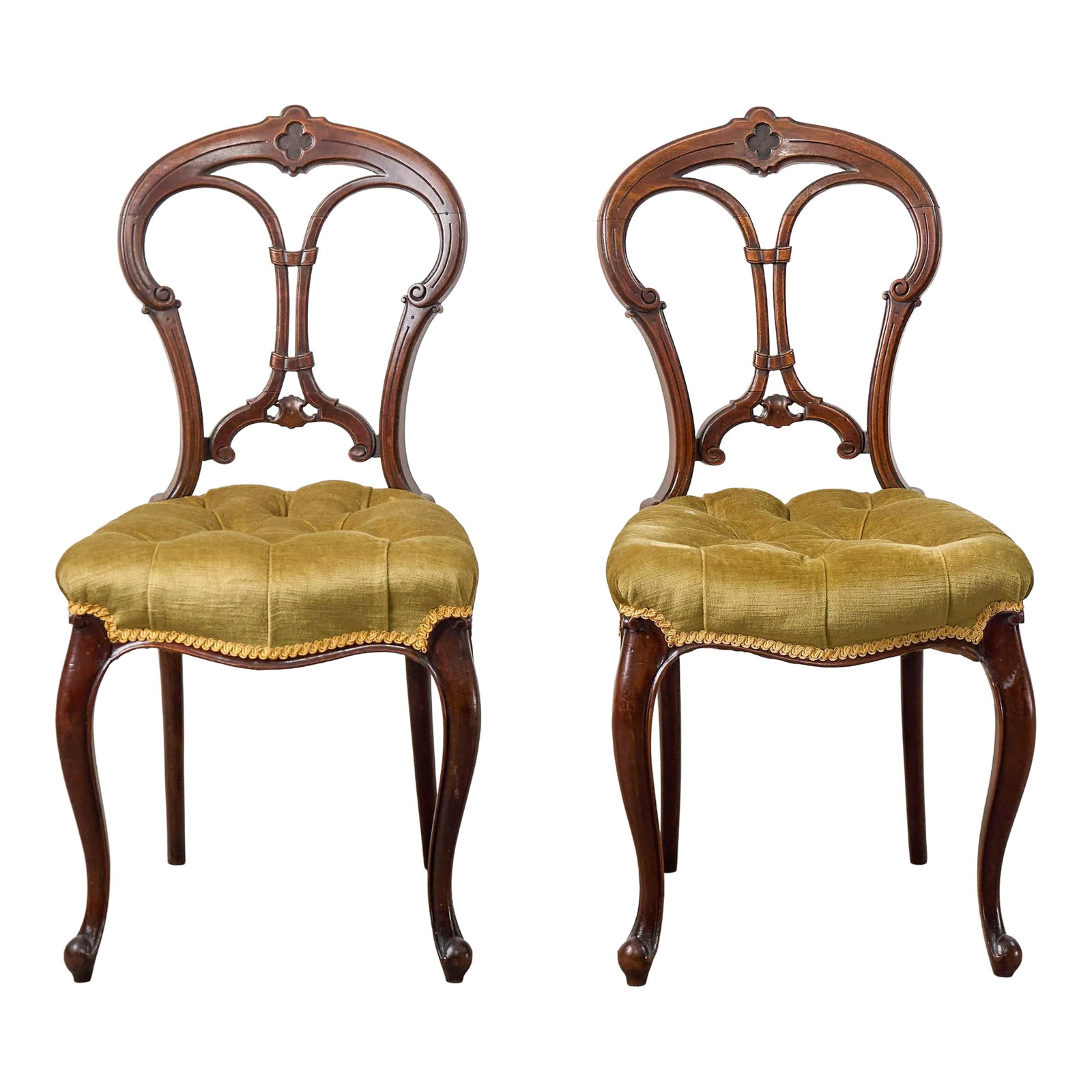 Pair of Antique Carved Chairs With Velvet Tufted Upholstered Seats: This pair of antique carved chairs features pierced balloon backs with hand-carved detailing. Each seat is cushioned and upholstered in plush olive-green velvet with deep tufting, finished with gold