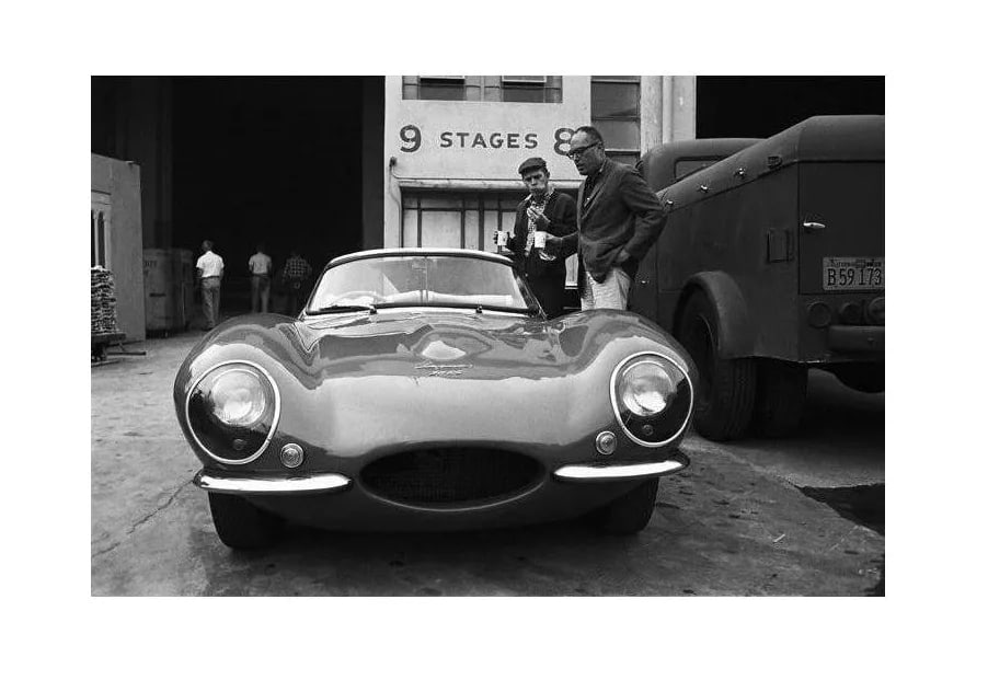 Steve McQueen and His Xk-Ss Jaguar With Director John Sturges 1960: Steve McQueen examining his 1957 XK-SS Jaguar with director John Sturges on the Goldwyn studio lot in Hollywood, 1960. 11" x 14" silver gelatin fiber based print signed on verso by the photographer, S