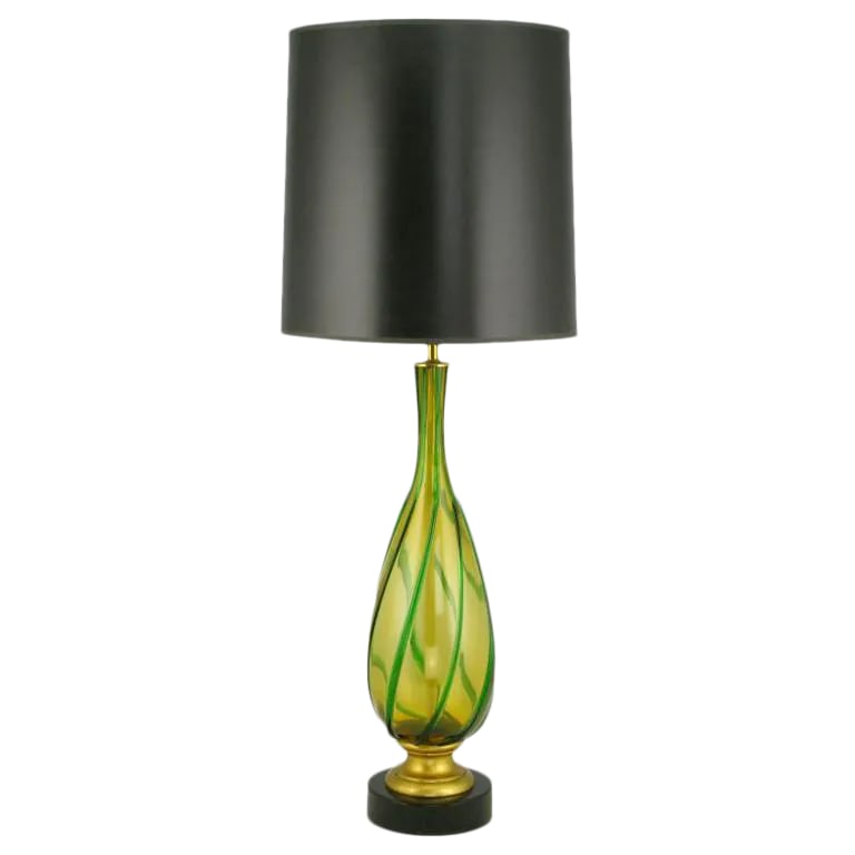 Italian Amber and Green Swirled Murano Glass Table Lamp: Beautiful amber and green Murano glass bodied table lamp. The vase form body is mounted on a gilt wood and black lacquered metal base. Sold sans shade. Condition: Alterations: Unknown Imperfections: