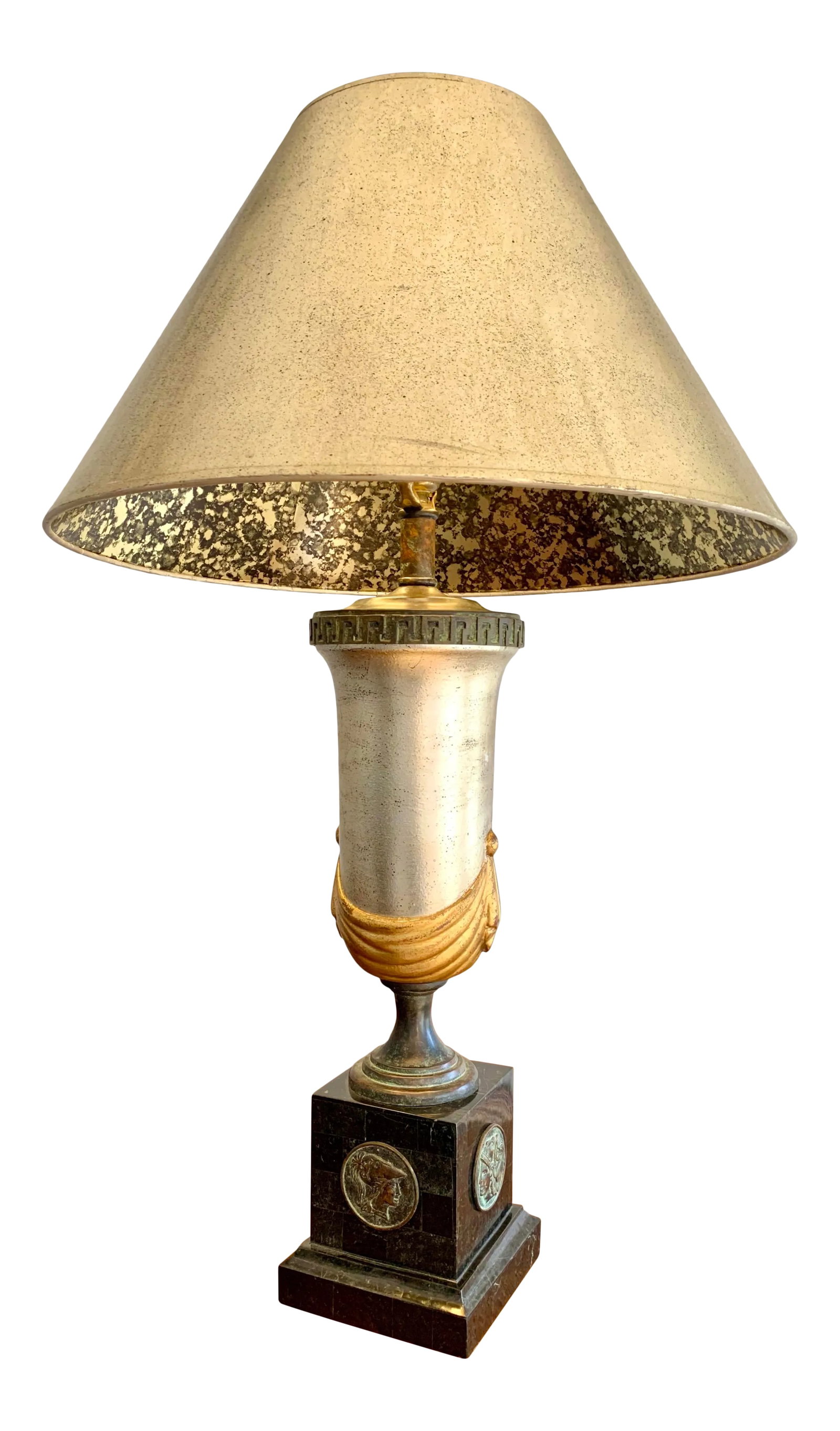 Maitland Smith Neoclassical Style Table Lamp: Striking lamp by Maitland-Smith in a neoclassical style. A silver and gold leaf trophy-style body with a greek key detail sits atop a marble base decorated with Roman profile medallions. Includes shad