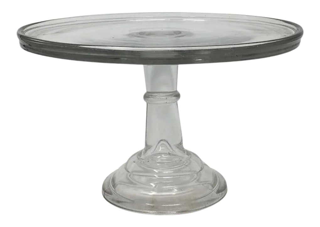 Antique Pedestal Glass Cake Patisserie Stand: This antique glass cake patisserie stand sits on a glass pedestal base. Perfect for displaying your culinary confections, this piece's simple, elegant look will mix with any decor. H 6.75 in. x Dm