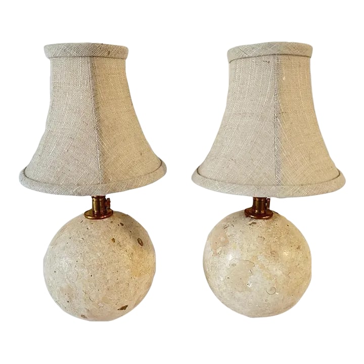 Travertine Ball Table Lamps - a Pair: Pair of Travertine Novona Ball Table Lamps, with Brass Sockets, Silk wired cable, pivoting on a Brass Ring base. Ball is adjustable to any movement. Lamps were manufactured and created at our studio.