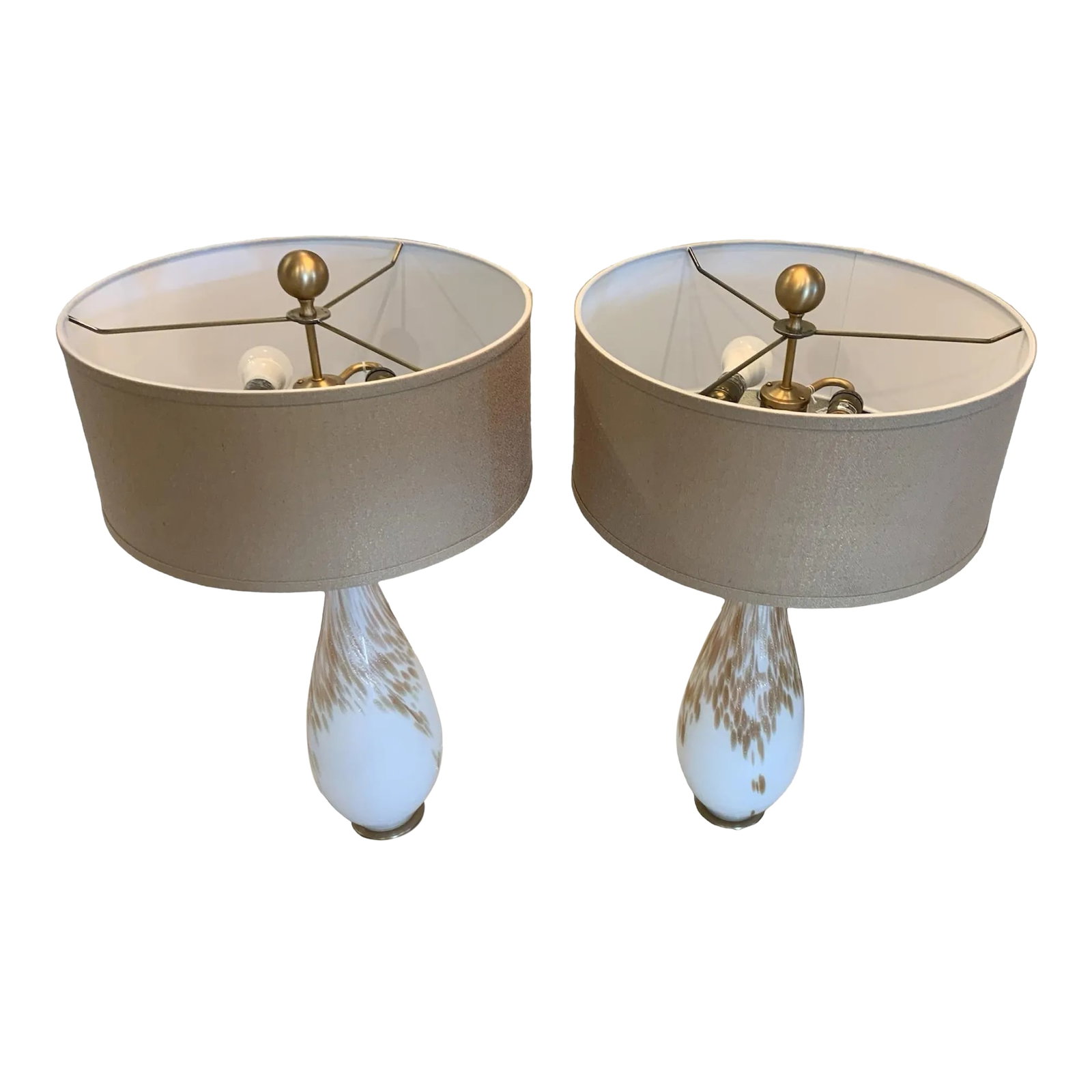 Pair of Cardoni Table Lamps: Gloss white glass featuring metallic golden bronze hues accented with plated brushed brass metal details and a thick crystal foot. The round hardback drum shade is a taupe bronze linen fabric with