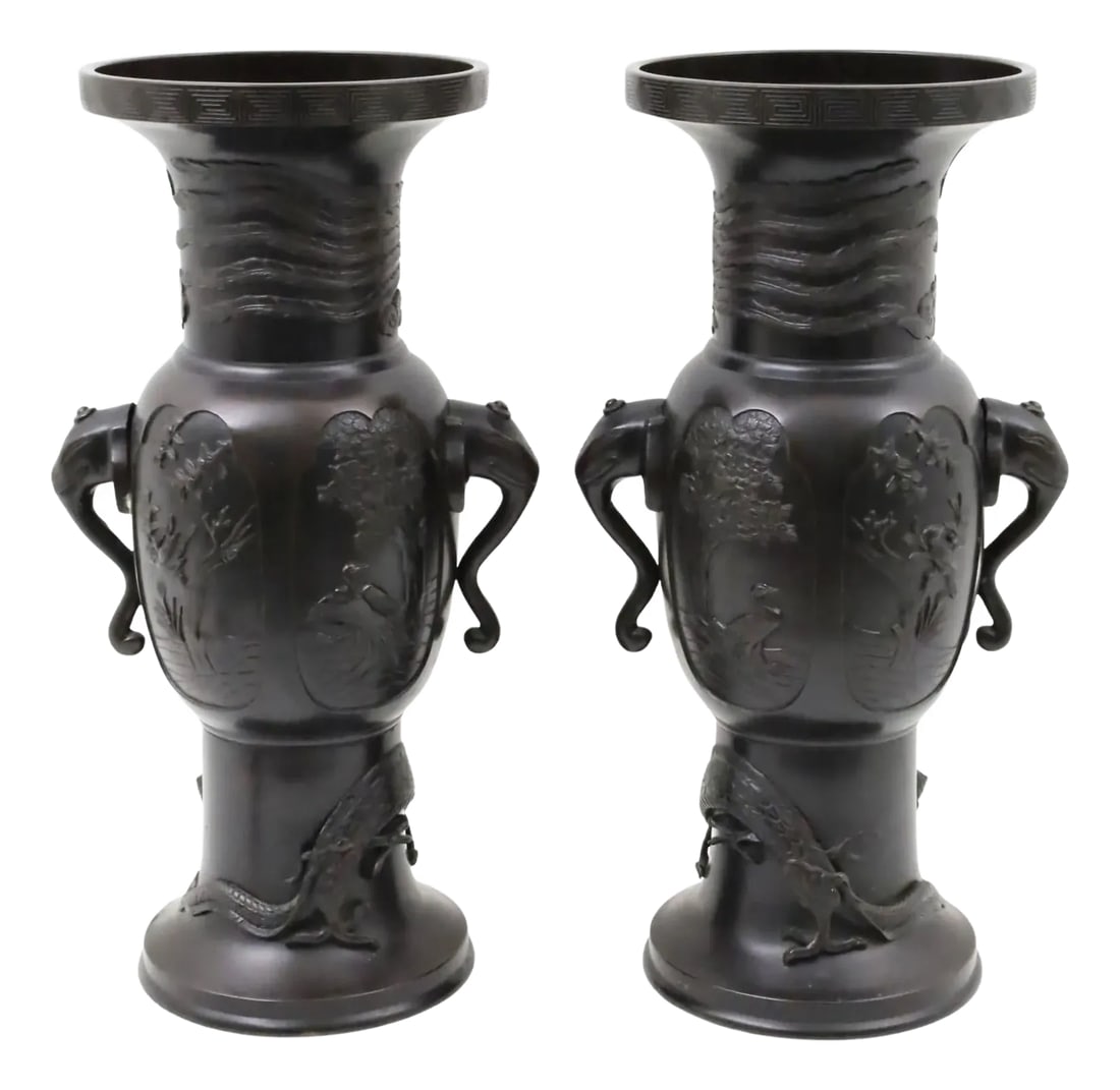 Large Meiji Japanese Patinated Bronze Vases - A Pair: Pair of fine Meiji period Japanese patinated bronze vases distinguished by their stylized elephant form handles, cartouches depicting exotic birds and dragon encircling the base. 22 inches tall.