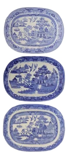 Antique English Willow Small Platters- Set of 3: This set of three mixed antique blue-and-white English Willow pattern platters depict the classic Willow pattern, inspired by a romantic Chinese folklore of two star-crossed lovers transformed into do