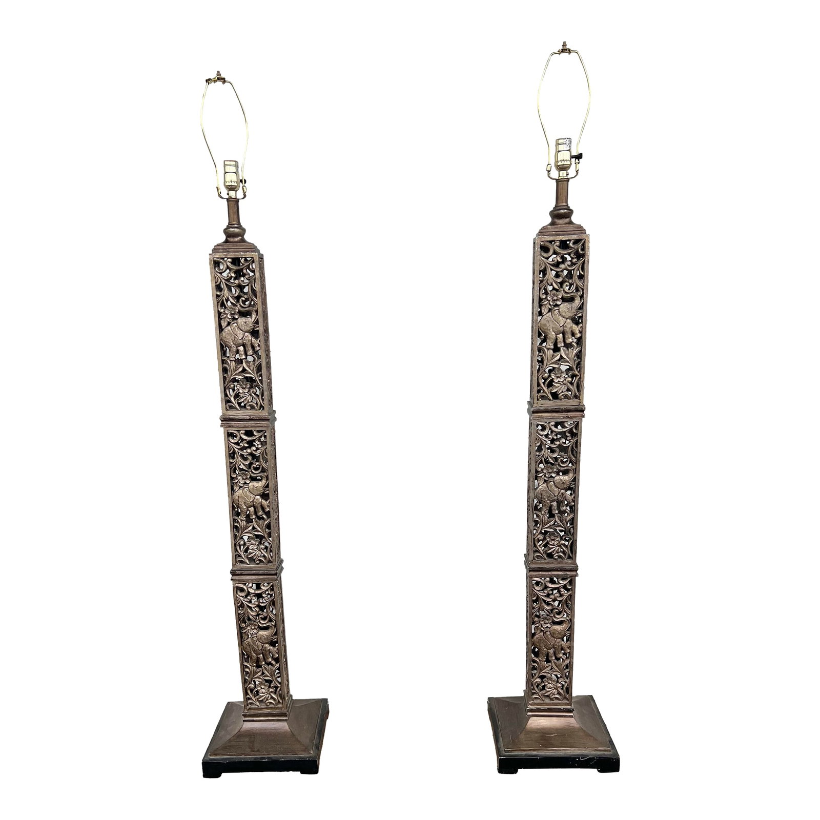 1990s Tall Floor Lamps With Elephants - a Pair: These lamps are tall, square columns with intricate, pierced carvings that prominently feature elephants. The design incorporates a traditional or safari theme and may be attributed to styles like