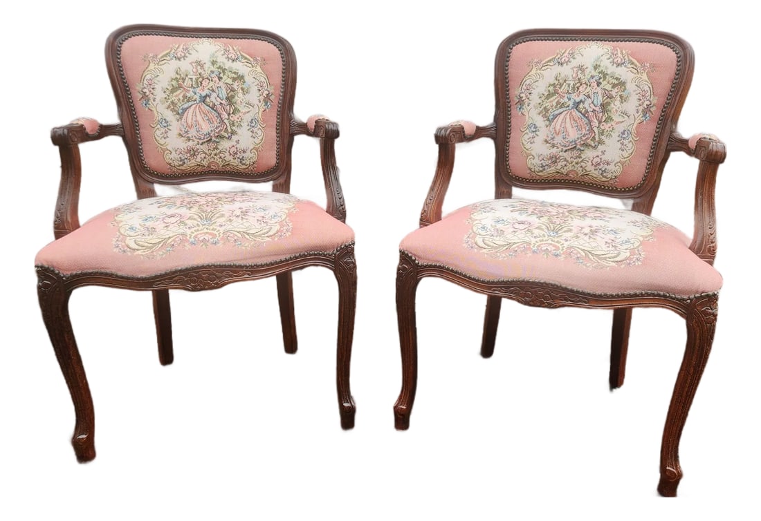 Pair of Vintage Louis XV Style French Provincial Open Armchairs With Pink Romantic Tapestry Upholste: A charming pair of vintage Louis XV Style armchairs featuring carved wood frames in a rich walnut-toned finish, graceful cabriole legs, scroll arms, and rounded backs. The chairs are upholstered in a