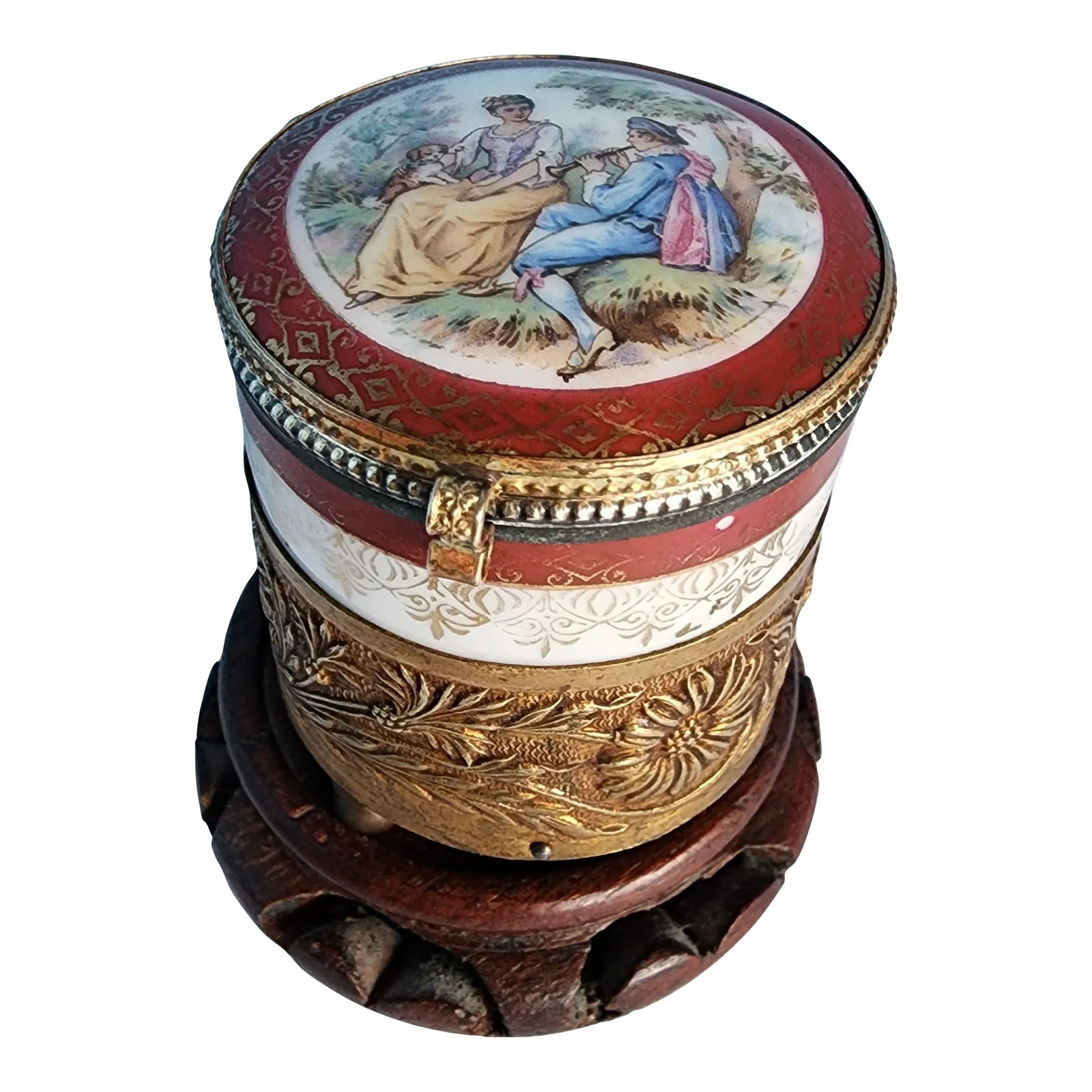 Early 20th Century French Music Box With Fragonard Scene on Lid and Brass Repousse Band: Petite French music powder box featuring a hand painted Fragonard scene on the lid, and a mirror inside. It plays a lovely tune possibly Rippling Waves by Schwensek. It comes with a carved wooden stan