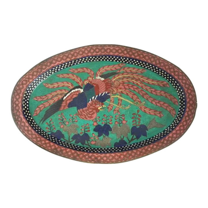 Antique Early Meiji Japanese Cloisonne Phoenix Bird Tray: An antique Japanese, Early Edo period, enamel copper tray. The oval shaped tray is enameled with a polychrome image of a Phoenix bird with flowers and leaves made in the Cloisonne technique. The borde