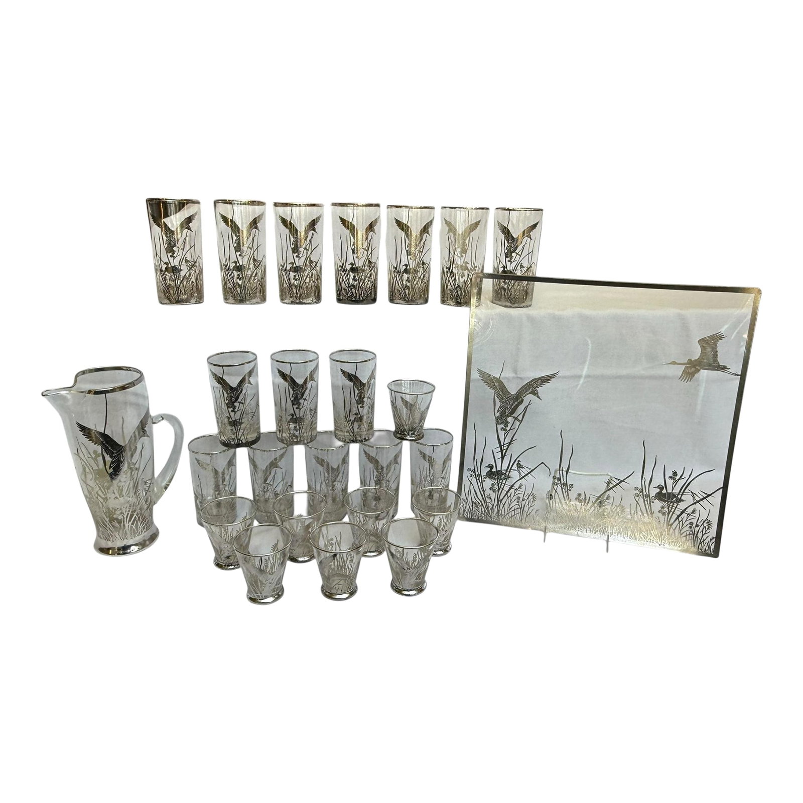 Mid 20th Century Barware Rockwell Silver Glass Ducks & Reeds Sterling Silver Overlay Set of 25 With: Offering a large matching set of mid-century silver overlay barware set with pitcher and large serving platter. Clear glass with a sterling silver overlaid waterfowl scene. Rockwell Silver Glass Mid 2