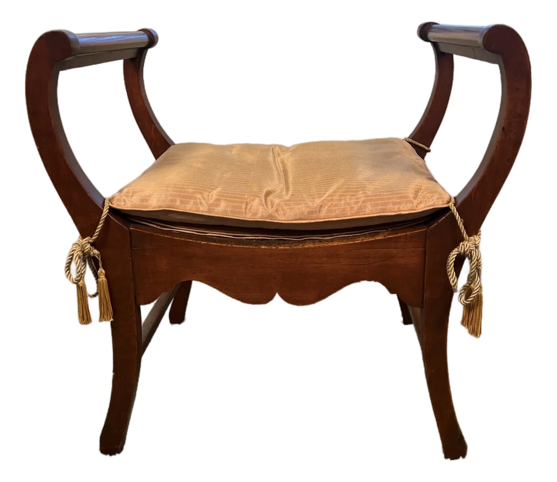 Late 20th Century Empire Revival Mahogany Side Bench With Striped Cushion and Tassel Ties: An elegant Empire Revival side bench featuring gracefully scrolled ends, saber-style legs, and a warm mahogany finish. The bench is topped with a tailored champagne-toned striped cushion, finished wit