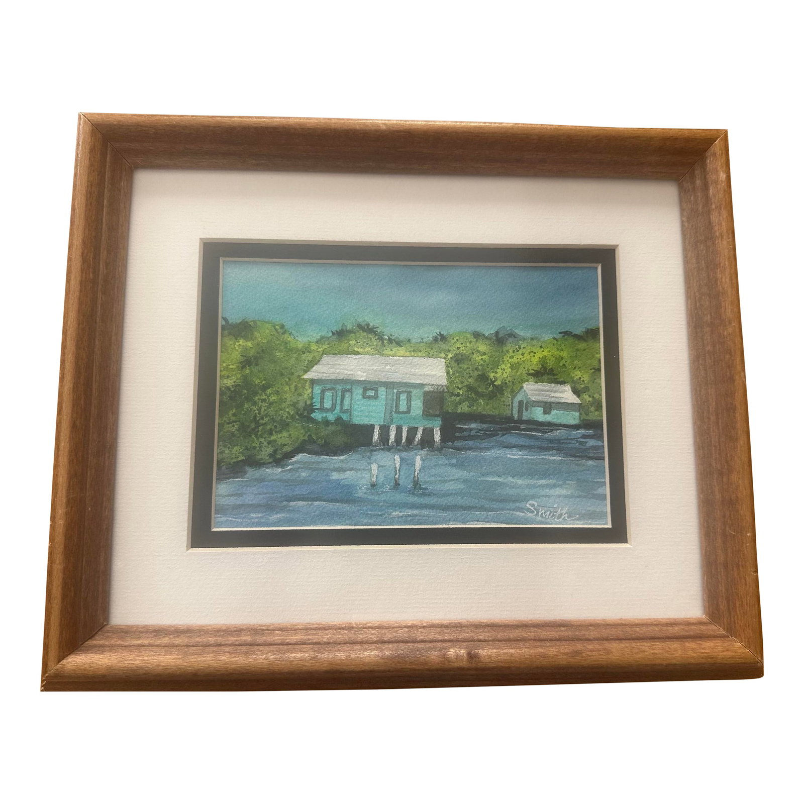 "Tidewater Cottages" Framed Signed Original Watercolor by Nancy Smith: Original watercolor coastal scene depicting stilted cottages along calm blue water, framed by lush greenery. The balanced composition and cool color palette evoke a relaxed seaside atmosphere. Framed