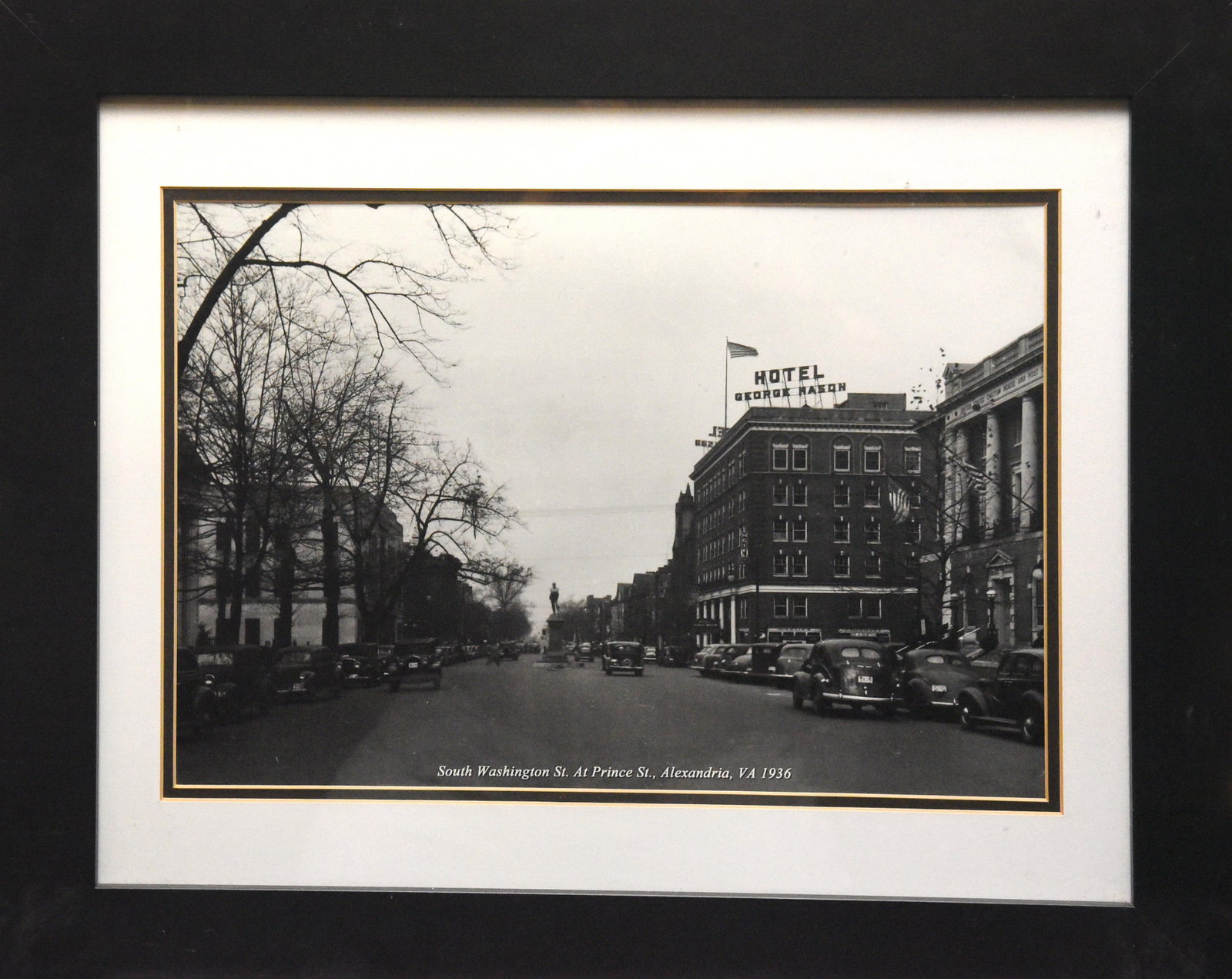 Hotel George Mason, Alexandria, Va, 1936, Framed: This photograph, sized 19" x 23", captures a street scene in Alexandria, Virginia, in 1936. The Hotel George Mason, a prominent building in the image, is the focal point, with its classic