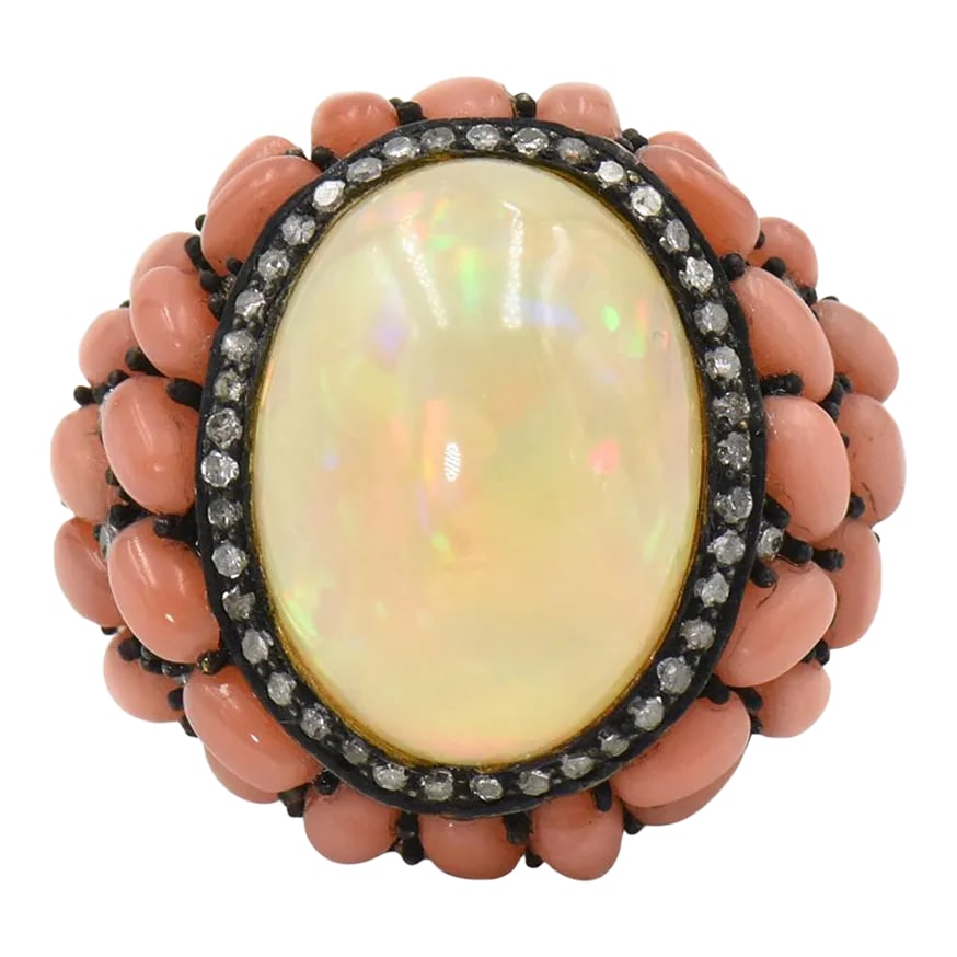 Opal Coral and Diamond Cocktail Ring size 9: This highly stylized ring features a cabochon Ethiopian opal in the center of a diamond frame set with interspersed coral and diamond design around the edges of the top. The ring is sterling silver wi