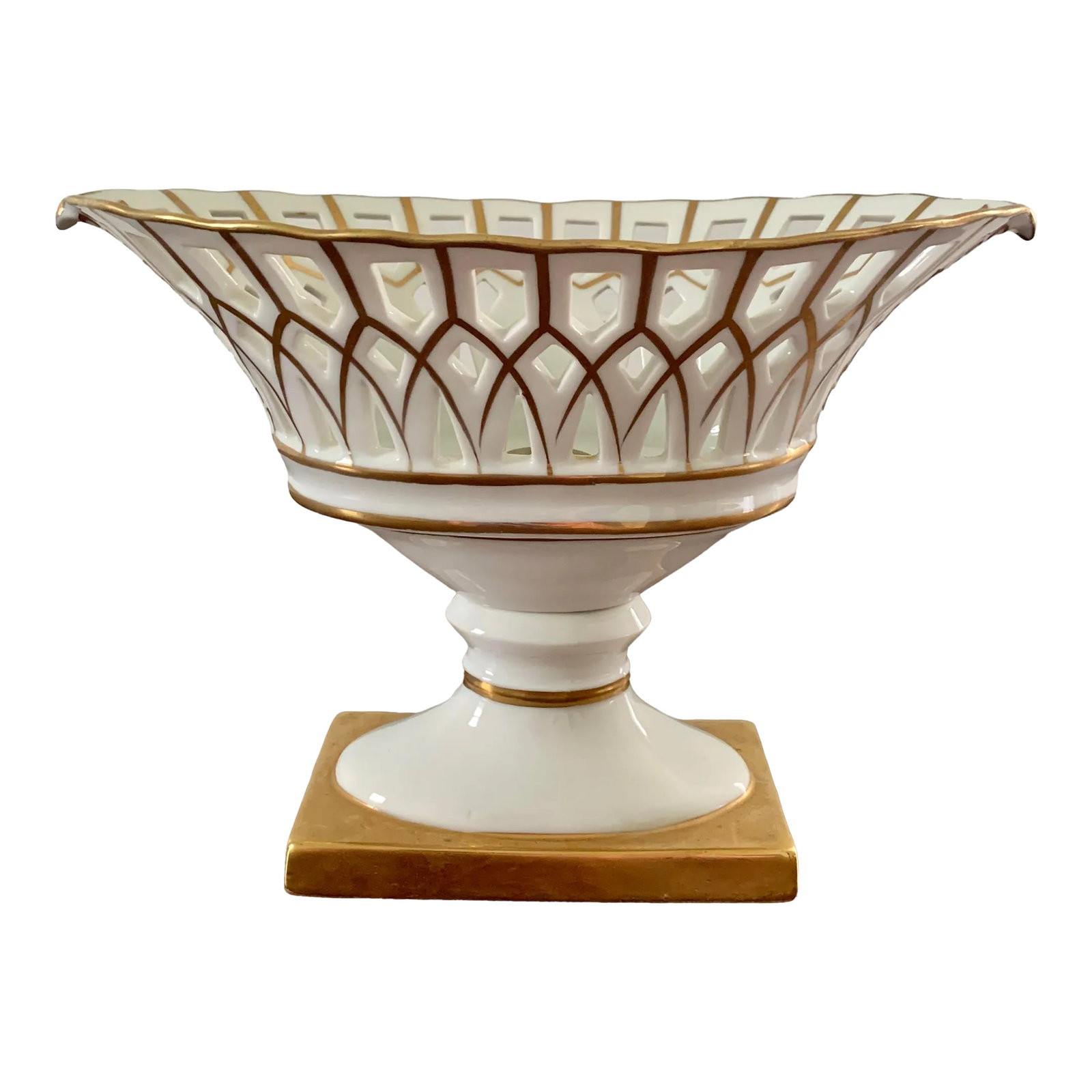 Reticulated Regency White Porcelain and Gold Gilt Basket Compote: A refined reticulated porcelain basket, executed in a neoclassical idiom with delicate openwork and restrained gilt ornament. The flared lattice body is raised on a sculptural rectangular base-an