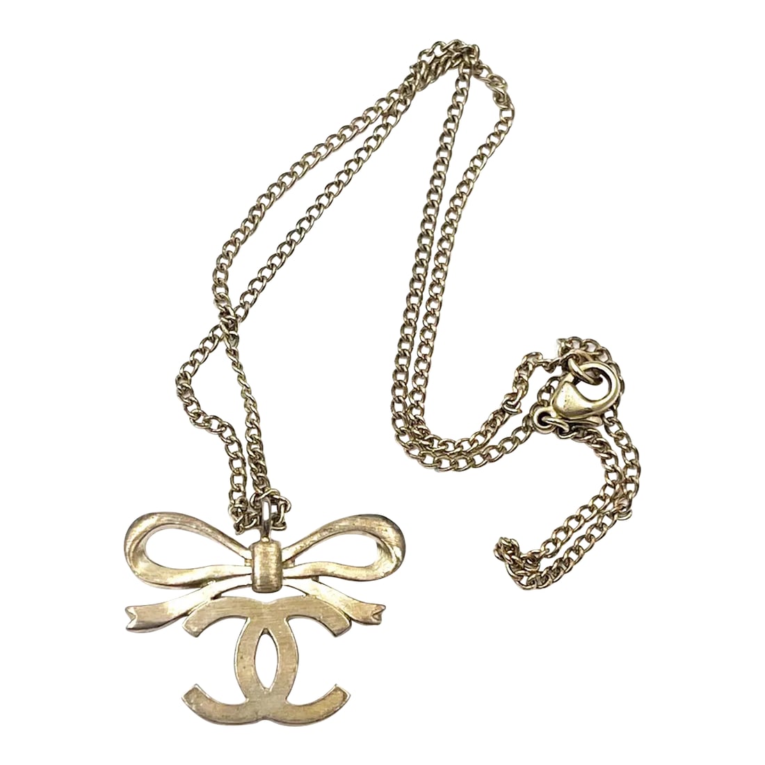 Chanel Light Gold Ribbon Bow CC Necklace: This is part of Chairish's Costume Jewelry assortment. Chanel Light Gold Ribbon Bow CC Necklace *Marked 05 *Made in France -Chain is approximately 16". -The pendant is approximately 1.25" x 0.9 "