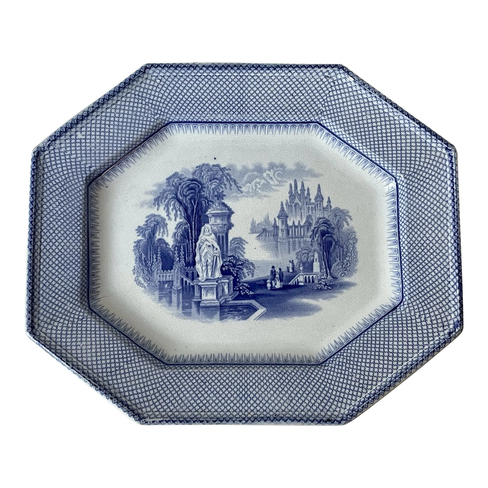 Antique Blue and White Transferware Ceramic Platter: This stunning platter is shaped octagonal with trellis border. The center is decorated with a classical statue near a bridge with strolling families and a castle in the background. Underside with