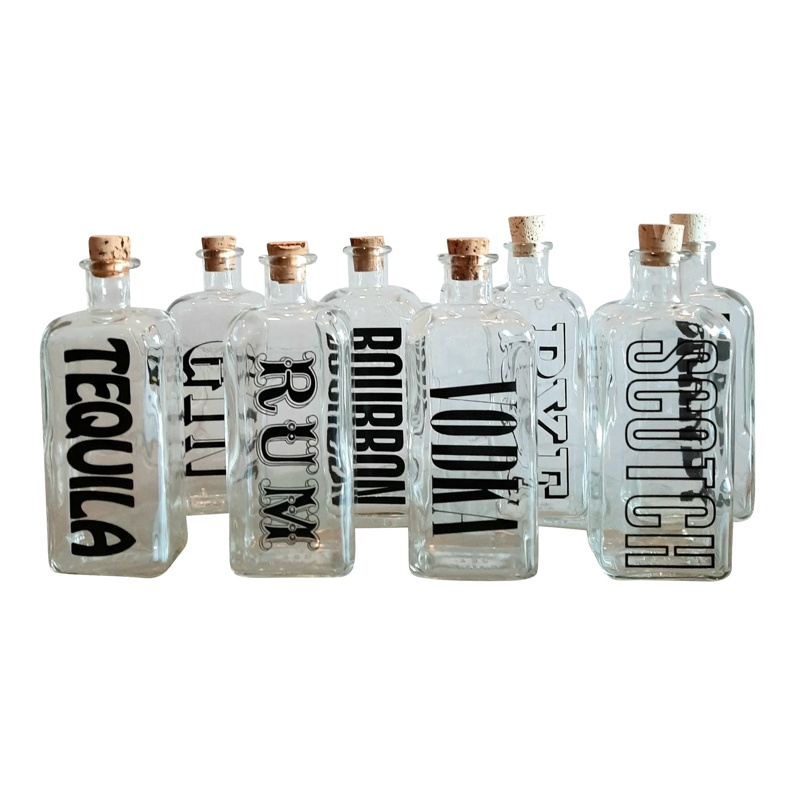 1960s Typographic Decanters- Set of 8: Vintage 1960's typographic decanters. Heavy glass construction with corks. Nice, bold graphic fonts. Made in the USA. Set includes... Gin, Vodka, Bourbon, Rye, Scotch, Tequila, Rum and Brandy