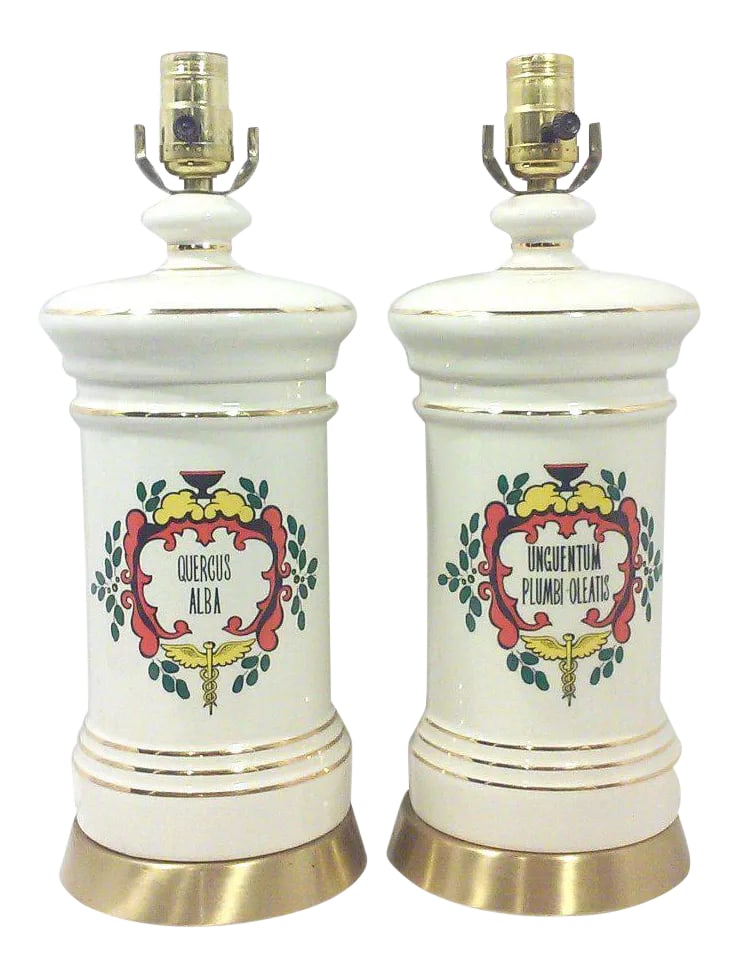Vintage Ceramic Apothecary Table Lamps-A Pair: A pair of apothecary style table lamps in off white ceramic with Rod of Asclepius design on the front of each lamp. These vintage lamps are in good vintage condition without damage or loss to the