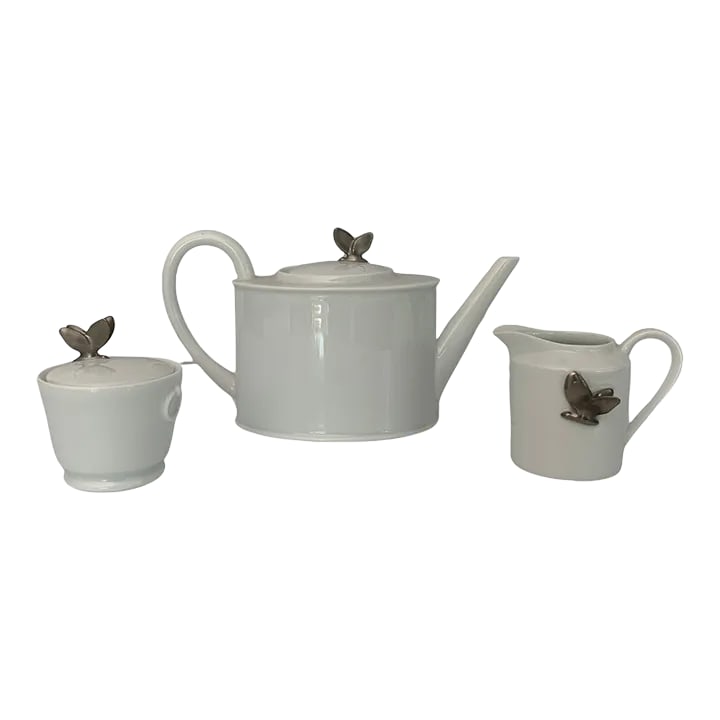 Mid 20th Century Limoges Tea Set- 3 Pieces: A silver porcelain butterfly adorns each piece of this white French Limoges tea pot, sugar and creamer. Made by Alexandre Chastagner. Size: Teapot- 5.5" h, 9.5" w, 4" d. Creamer- 3" h, 4" w, 3" d. Sug