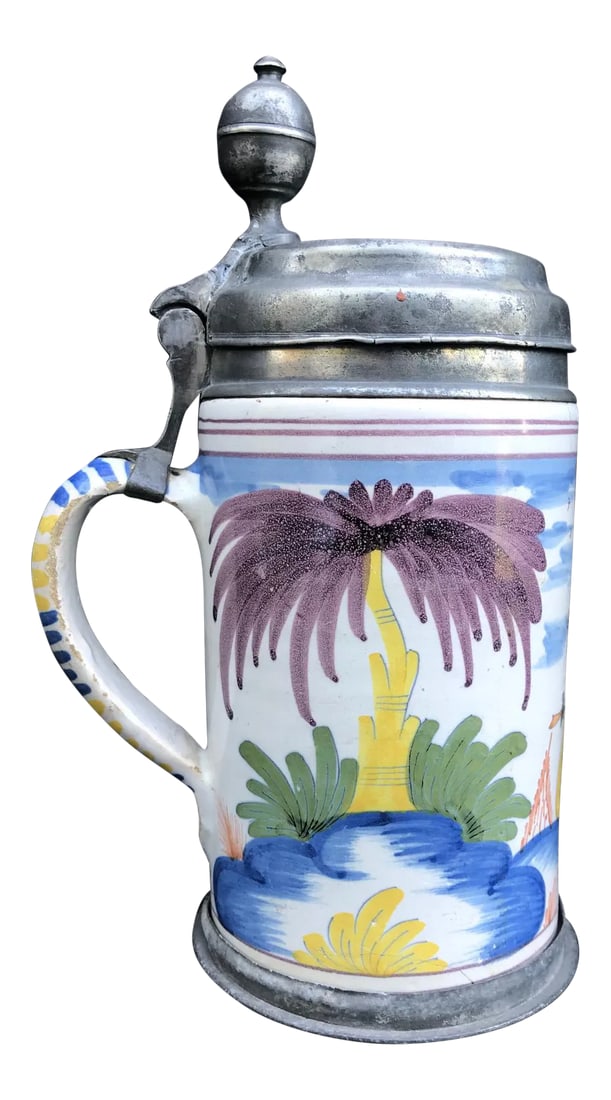 18th Century German Faience Polychrome Pewter-Mounted Tankard in Columnar Form: This tankard from the 3rd quarter 18th century is of cylindrical form with the handle mounted in pewter. The place of origin is probably Nurnberg. It is polychrome painted with a stylized landscape