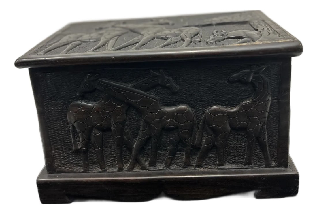 African Blackwood Relief-Carved Box (Tanzania): This is a substantial hand-carved African Blackwood storage box from Tanzania, featuring deeply carved relief panels of giraffes and savanna motifs on all four sides and on the lid. The box is crafted