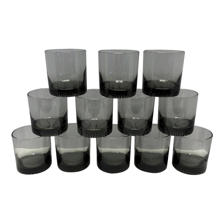Mid 20th Century Mid-Century Scandinavian Smoked Glass Rocks Tumblers With Textured Bases - Set of 1: A striking set of twelve mid-century Scandinavian-style smoked glass rocks tumblers, distinguished by their weighted bases and subtle textured detailing. The clean cylindrical form and deep charcoal