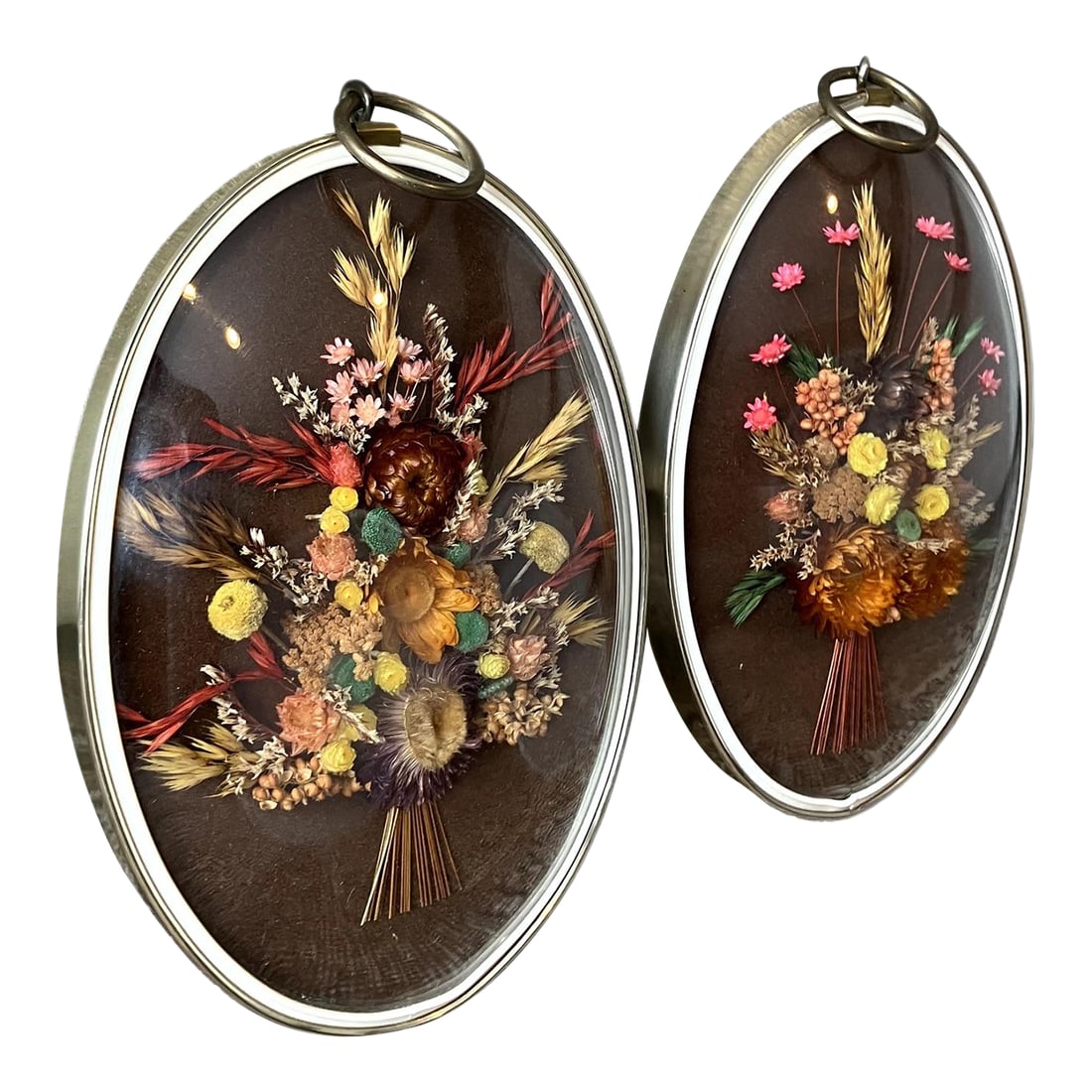 Pair of Vintage Oval Cideart Belgium Dried Floral Arrangements in a Convex Glass Dome Frames: These are vintage framed dried flower arrangements made by a Belgian company called Cideart, often referred to as "bubble glass" or "domed glass" art. They were a popular home decor item, especially
