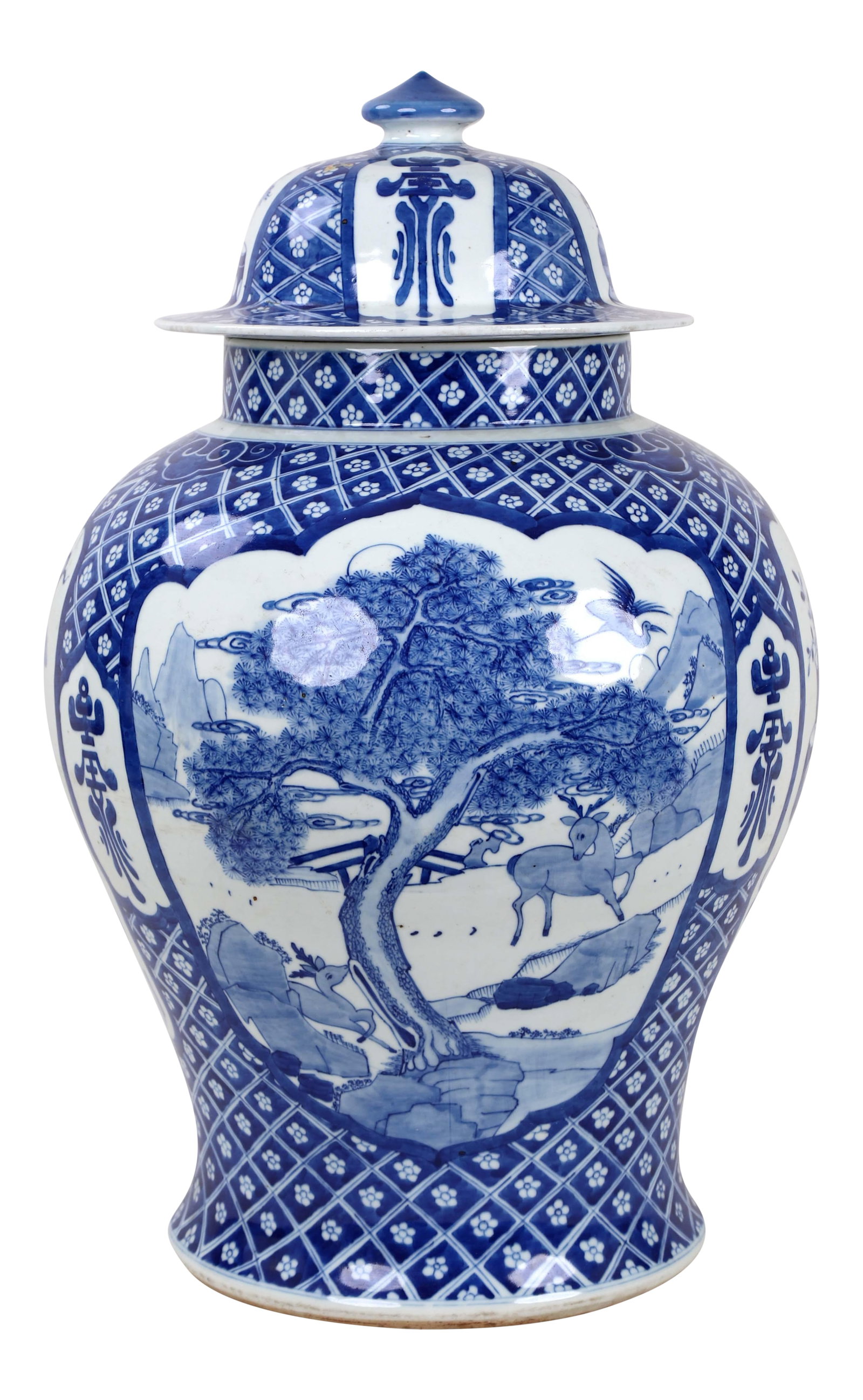 Early 20th Century Vintage Blue White Temple Jar: A windowed scene depicting deer playing around a tree in an oriental landscape. A crane flies overhead and a bridge sits in the distance. Diamonds containing small flowers frame these windows.