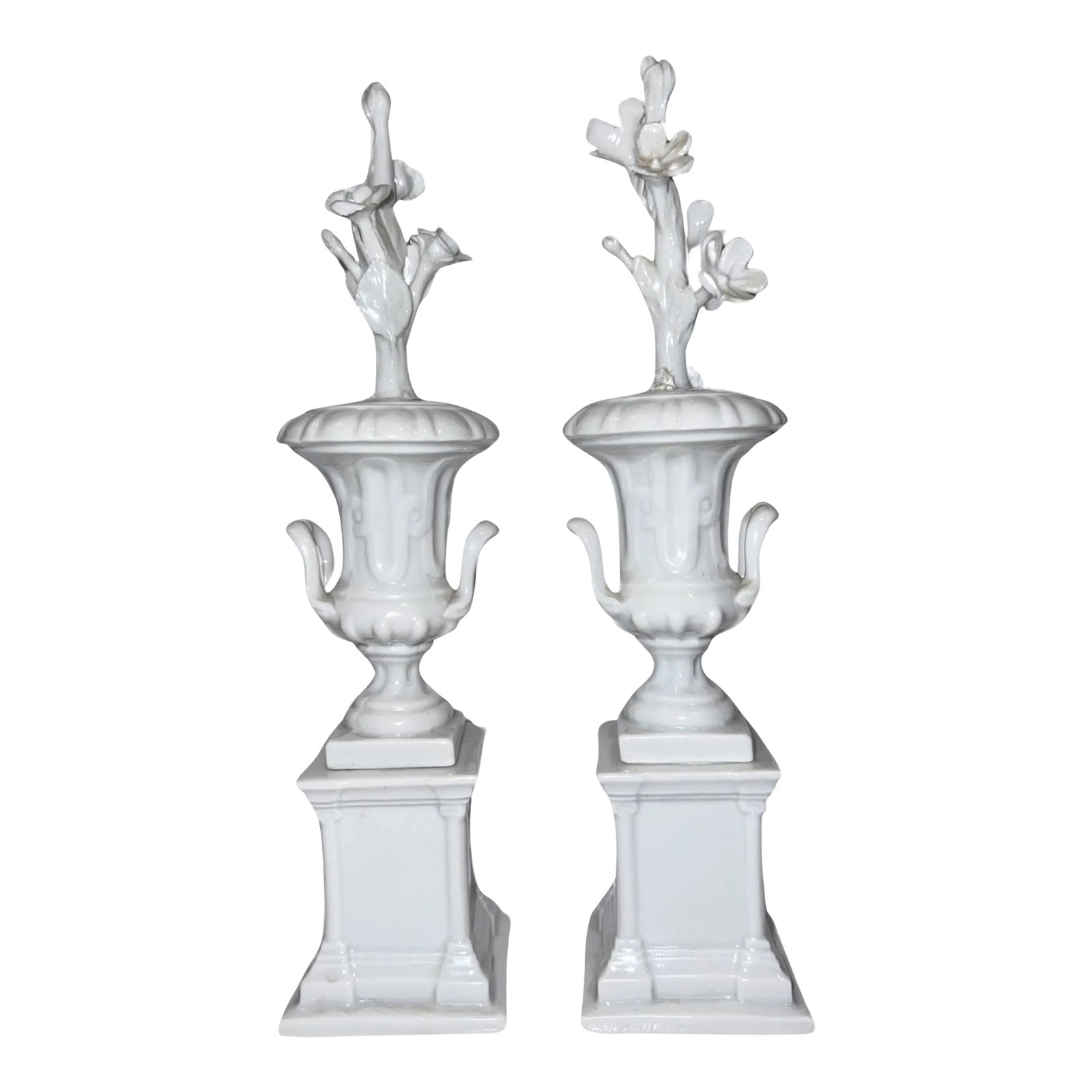 Pair, Cabinet of Curiosity Neoclassical Style Blanc De Chine Porcelain Urns: Italian, 20th century. A pair of petite blanc de chine porcelain urns with floral stem motif extending from each. Marked to underside with the Capodimonte blue mark. Condition: Alterations: Original