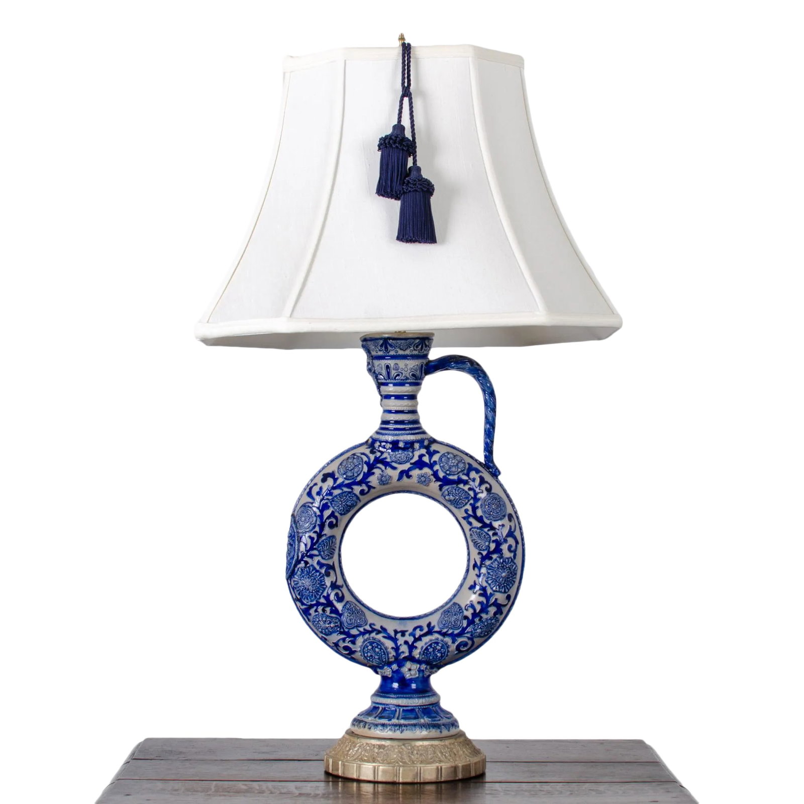 Late 19th Century Westerwald Ring Jug Lamp: A late 19th or early 20th century Westerwald ring jug converted to a lamp. Bellarmine face on tapering neck, with rope-twist handle, molded flowering vines and armorial roundel, with reeded foot.