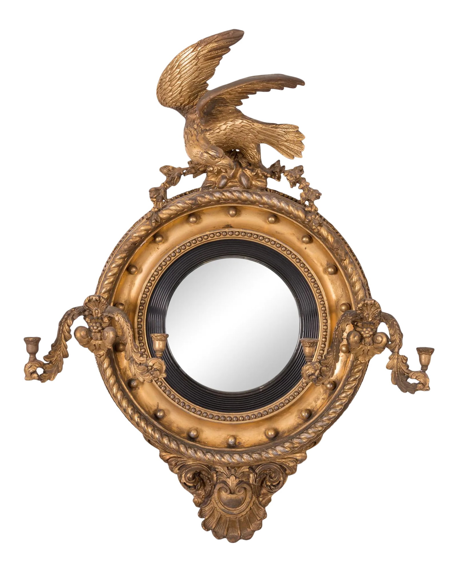 Regency Giltwood Convex Girandole Mirror: A Regency giltwood convex girandole mirror. The 13 inch convex plate with ebonized reeded surround is mounted in a concave frame with beaded and rope edges and ball spacers. The eagle mounted atop