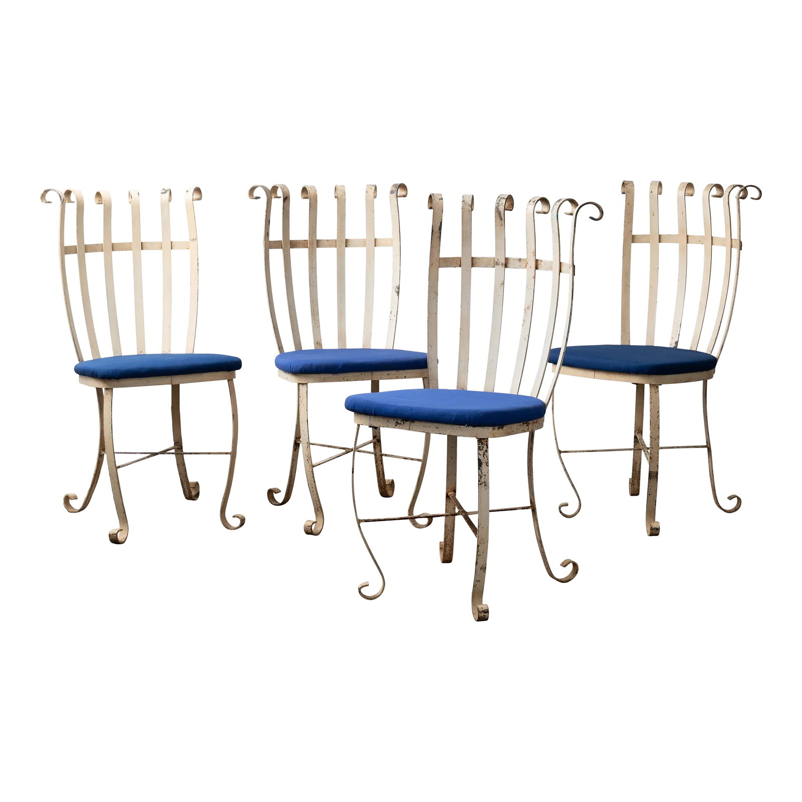 Scrolled Wrought Iron Chairs - Set of 4: A set of four scrolled wrought iron chairs in cobalt blue outdoor fabric, circa 1940s. each chairs measuring 16 inches wide by 20 inches deep by 36 inches tall Condition: Alterations: Original