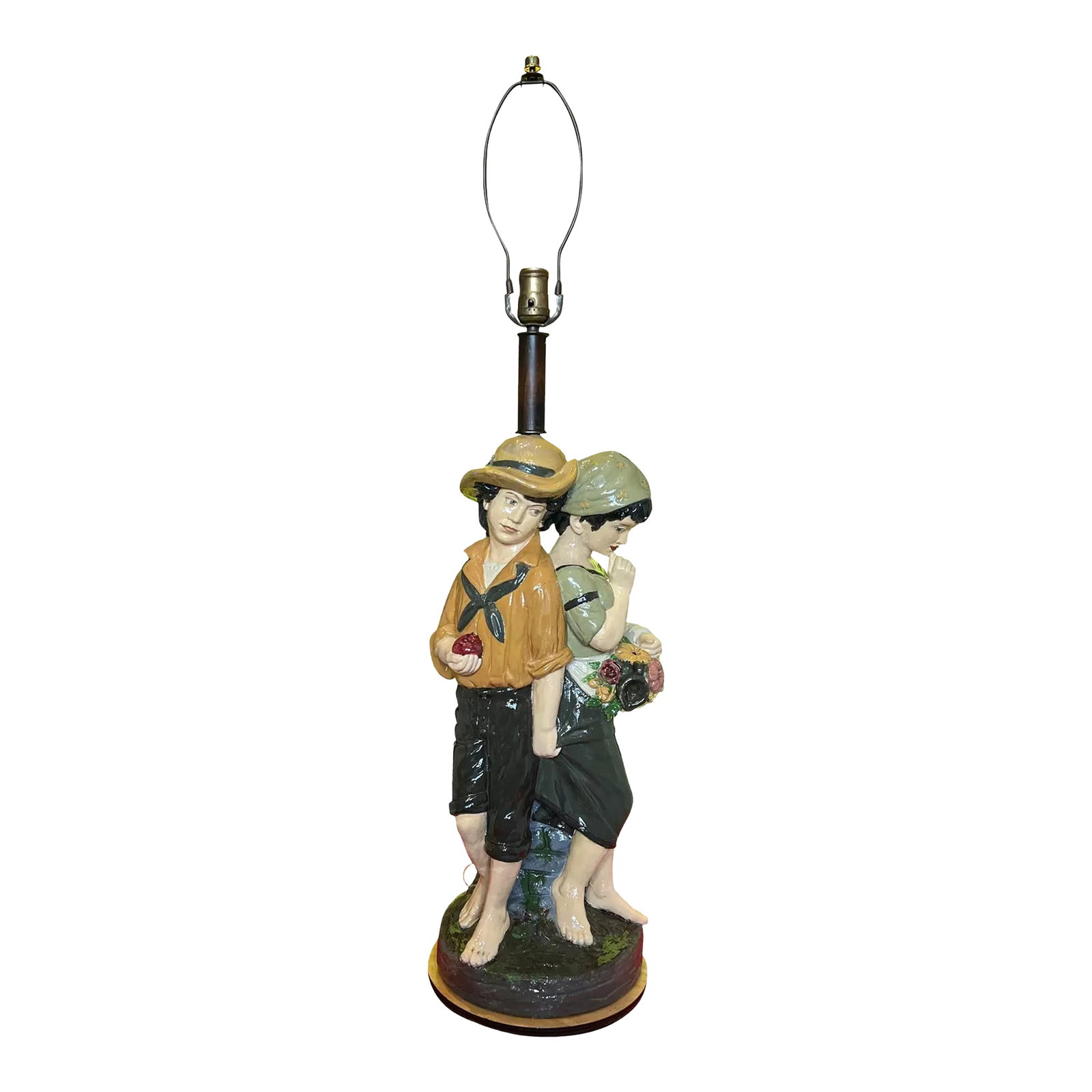 Mid Century Chalkware Lamp- Village Children: Two children-back-to-back, yet intimately connected-form the heart of this mid-century lamp. The boy stands, barefoot and tousle-haired under a yellow hat, a dark scarf knotted loosely around his neck