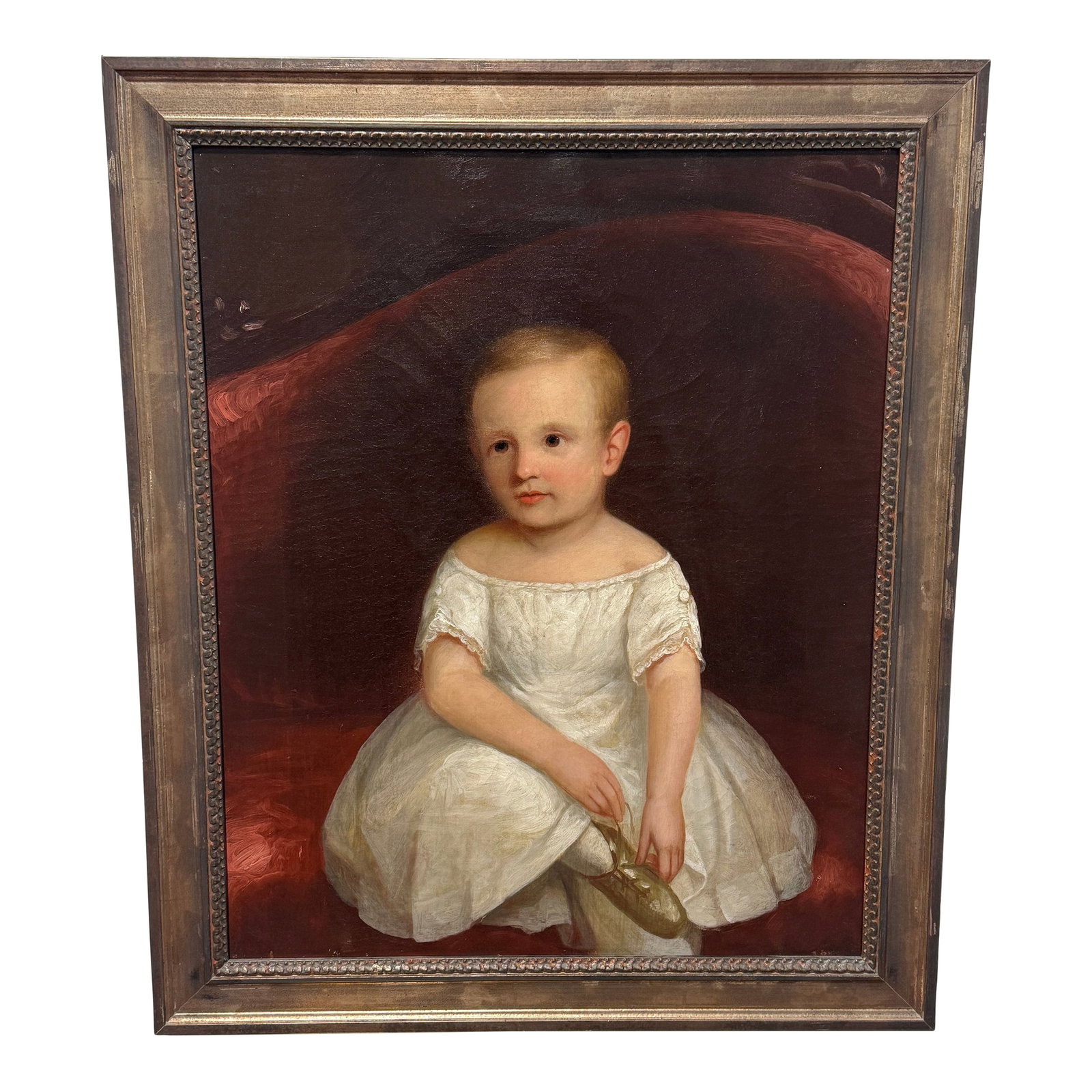 American Folk Art Portrait of a Young Child Holding a Slipper, C. 1830-1850: American Folk Art Portrait of a Young Child Holding a Slipper, c. 1830-1850 Oil on Canvas - In later Italian Frame. Measures: 31 5/8 * 26 5/8 in. A cherubic young child sits serenely against a plush r