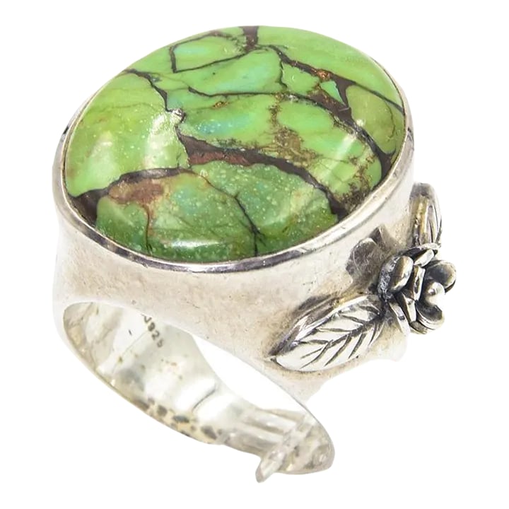 Large Turquoise Sterling Silver Ring With Flower: Large oval turquoise bezel set in a sterling silver mounting that has a raised flower and leaf on the side of the ring. Marked 925. US size 10. Approximately 1" wide by 1.08" tall x .40" depth not inc