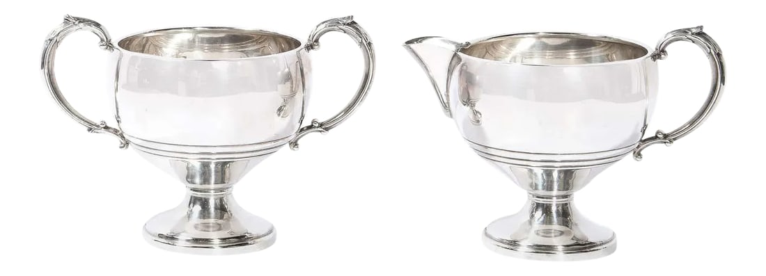 1940s Art Deco Sterling Sculptural Streamlined Handled Sugar & Creamer - A Pair: This elegant sugar and creamer set was realized in the United States circa 1940. It features a creamer with a circular base; a rounded body; and a streamlined handle. The sugar caddy is of a similar